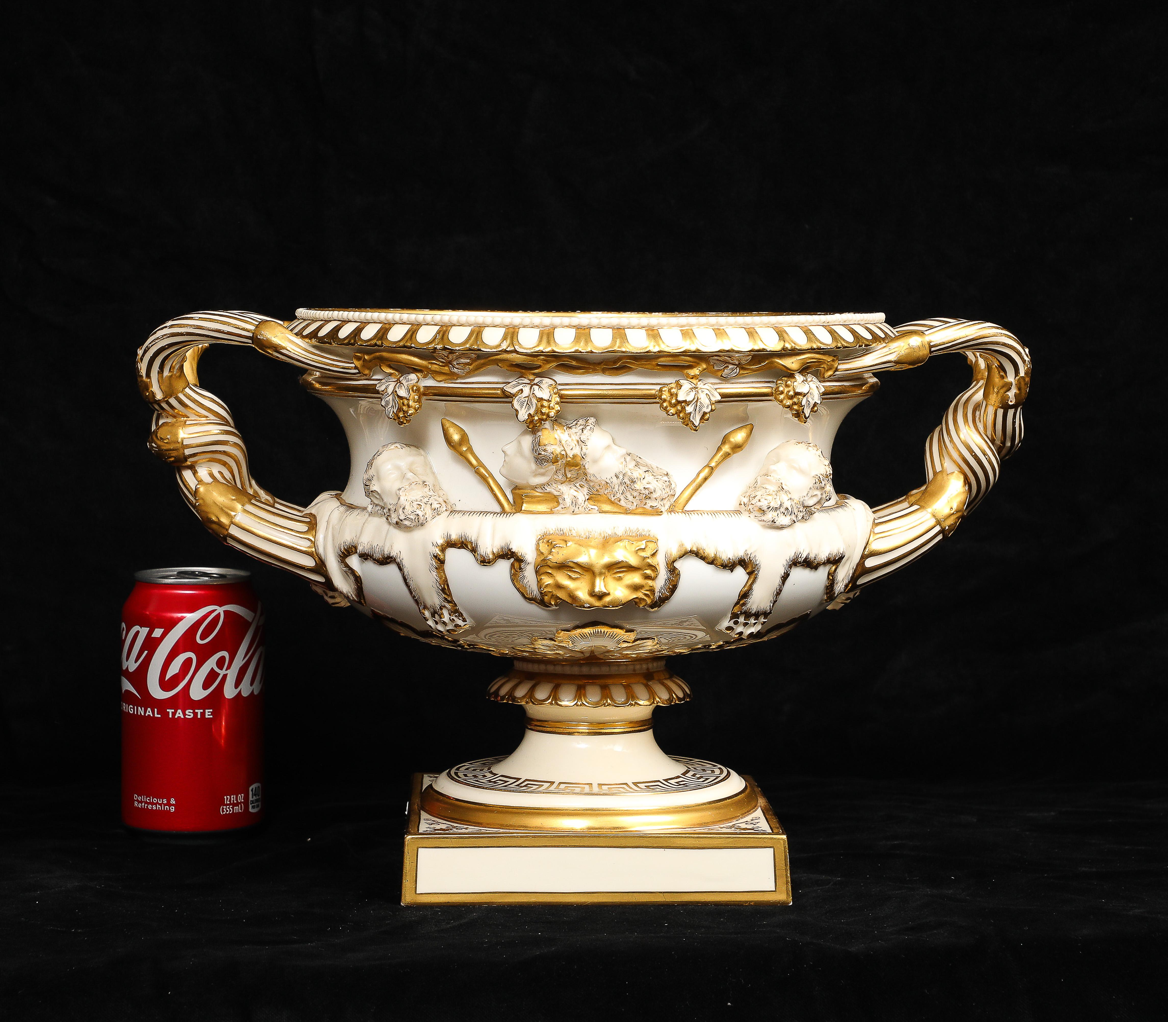 A Royal Worcester Porcelain Double-Handled Urn/Vase/Ice Bucket/Champagne Bucket with Relief Soldier and Military Head Decoration, Hand-Gilt with 24k gold. The urn is formed with an ovoid body supported on a circular spreading foot set upon a square