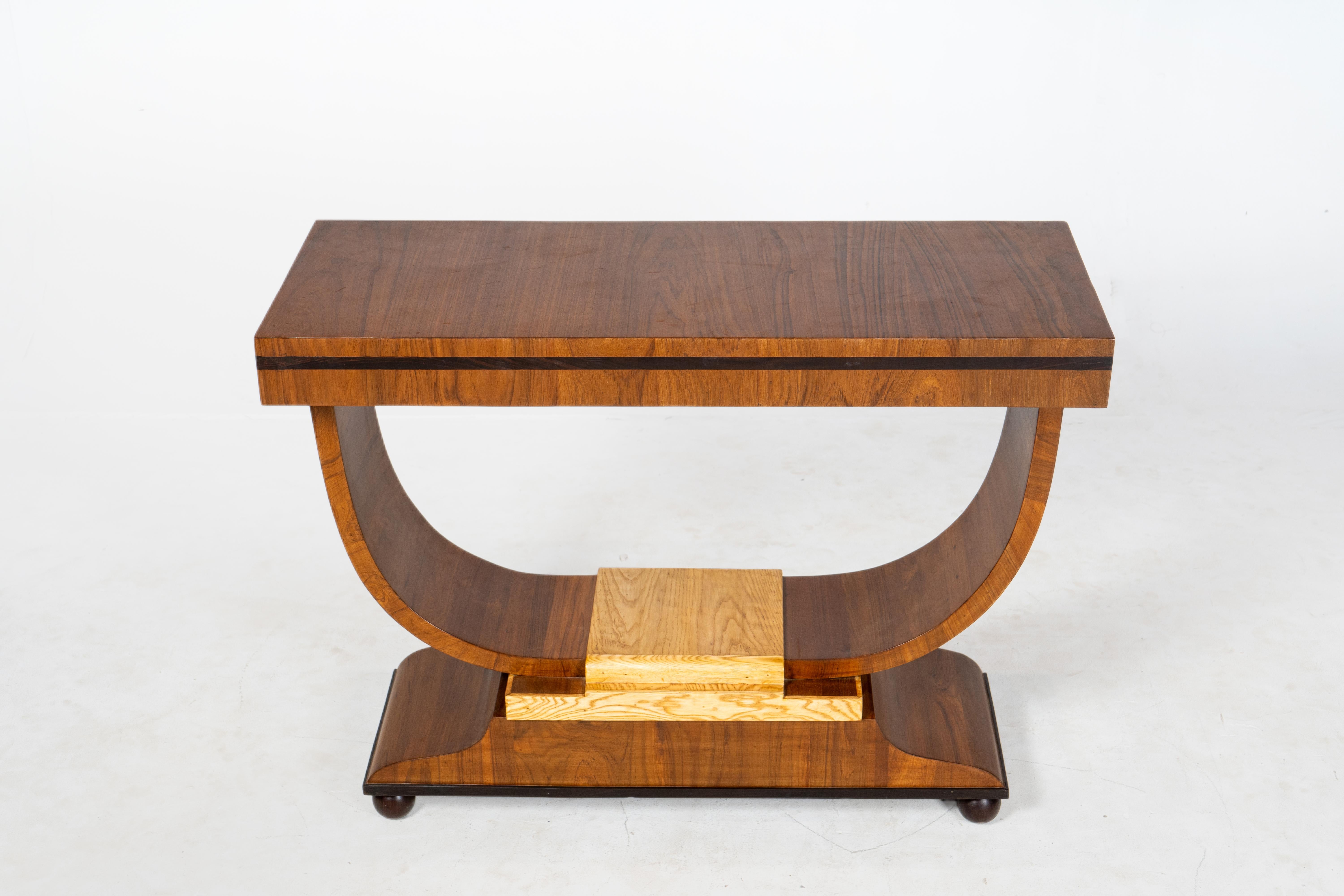 This exquisite Indian Art Deco console table beautifully blends modern design with luxurious craftsmanship. The elegantly curved base and squared off and chunky top makes a striking visual statement. The rich teak of the tabletop and arms contrasts
