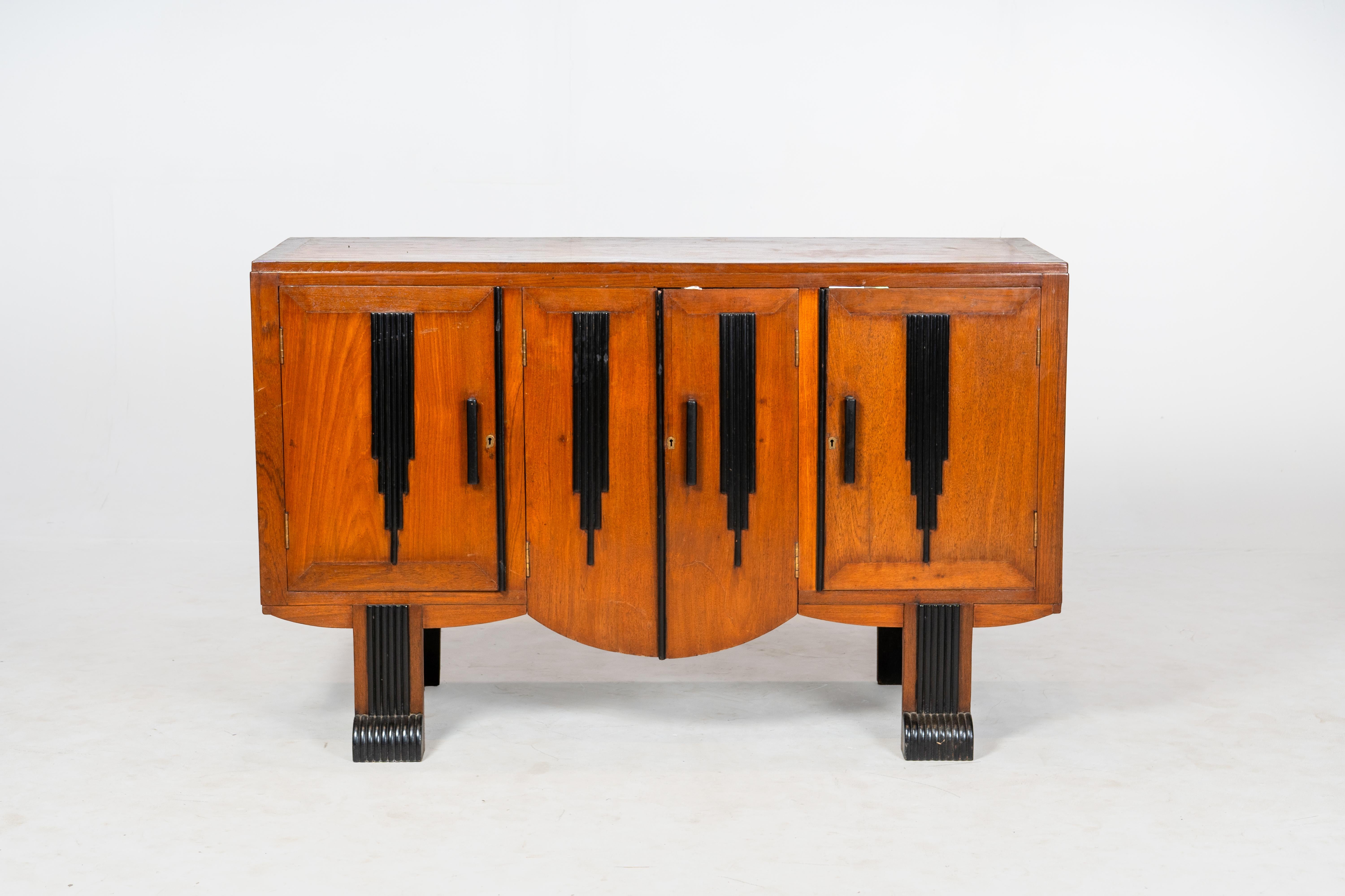 This vintage Art Deco sideboard features a bold geometric design, with four paneled doors adorned with striking black stepped inlays. The warm wood finish contrasts beautifully with the dark detailing, highlighting the streamlined elegance