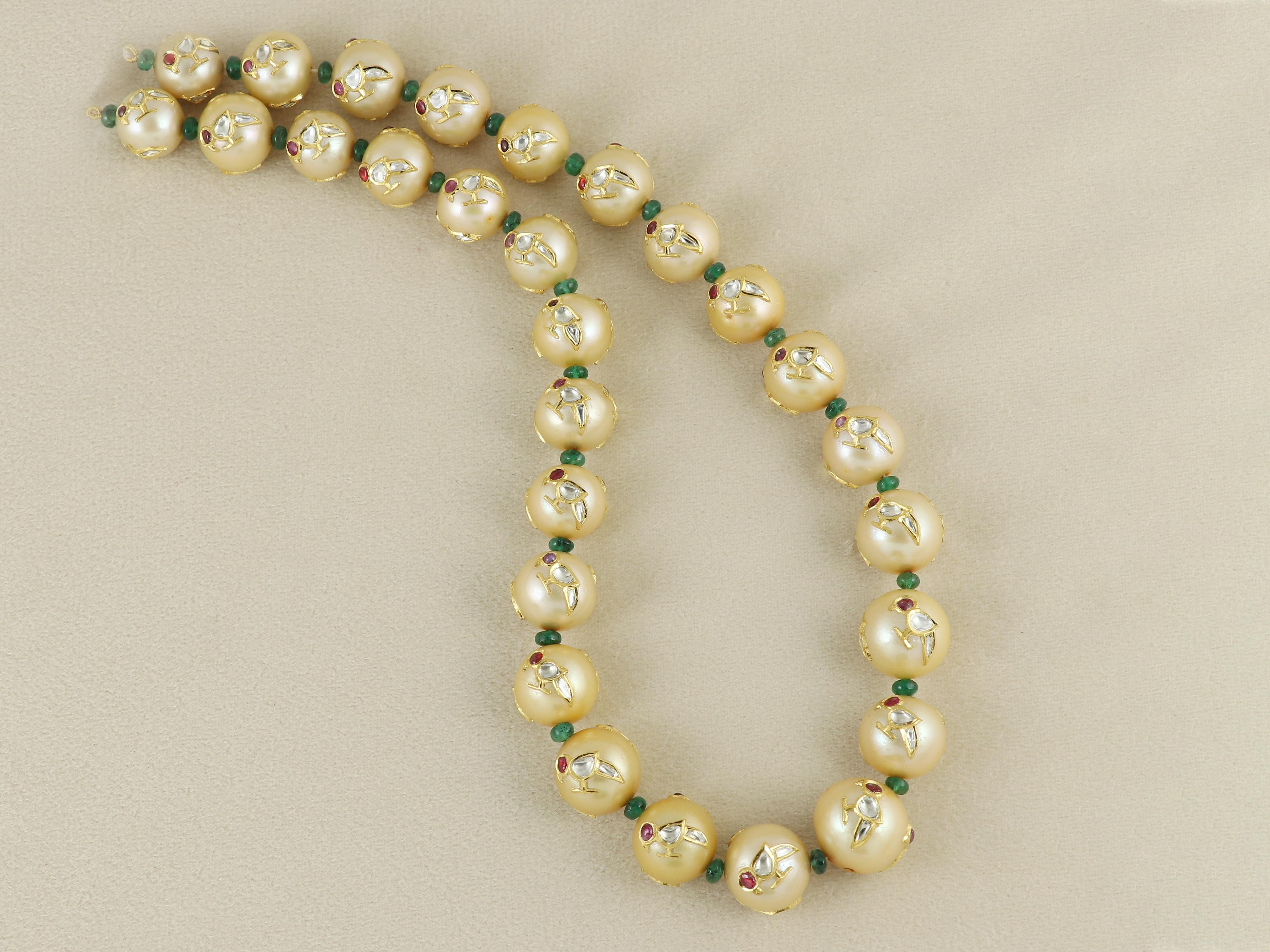 Este collar artesanal, extraordinaria expresión de la artesanía tradicional, presenta un collar de luminosas perlas naturales de los Mares del Sur, cada una de ellas incrustada tres veces con motivos de pájaros finamente detallados, una hazaña poco