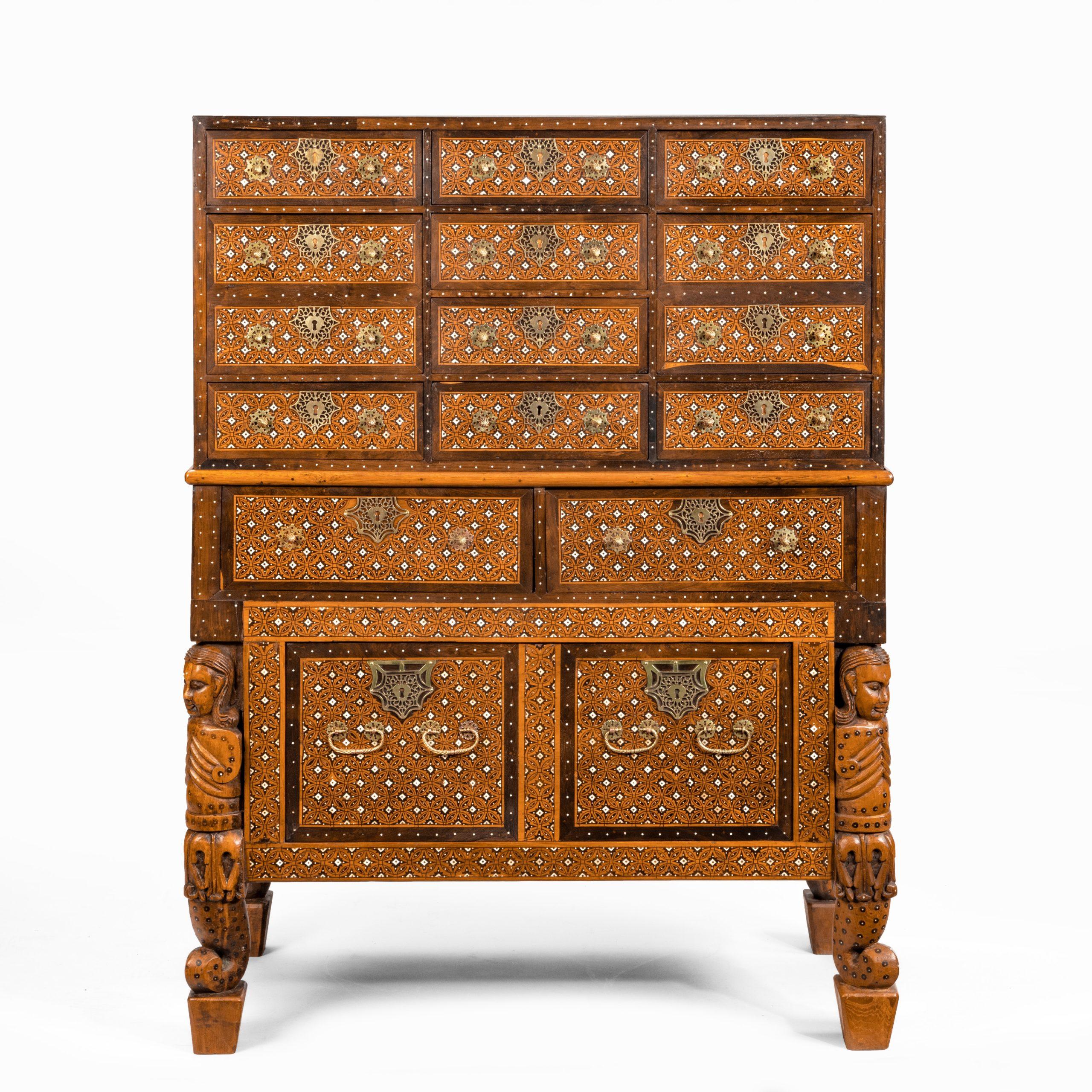 This chest on chest is of rectangular form in two sections. The upper section has twelve similar drawers in four registers and carrying handles on the sides. The base has a pair of frieze drawers above a single deep drawer, disguised as a pair, with