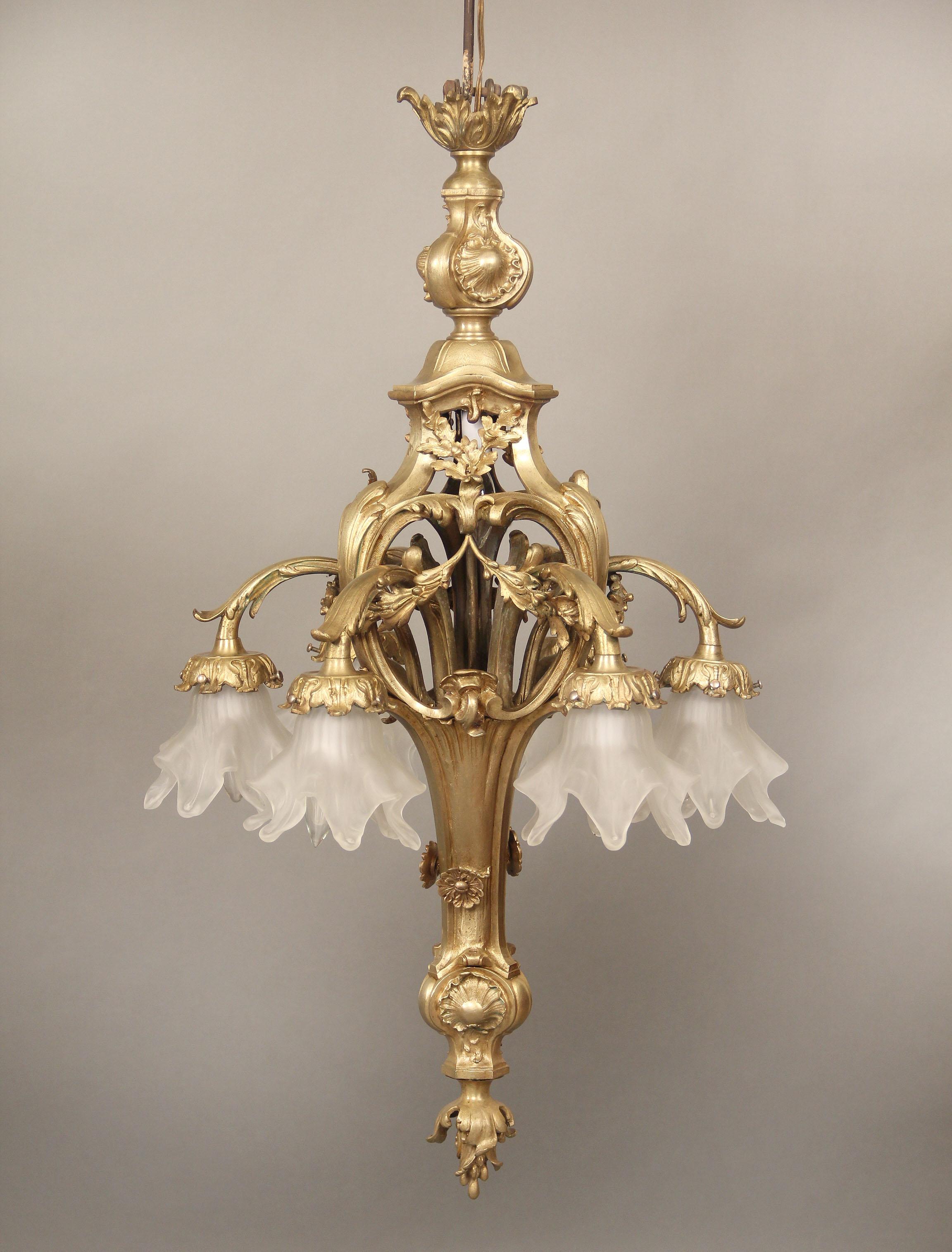 An Interesting Early 20th Century Gilt Bronze Six Light Chandelier

The body and arms designed with bronze acanthus leaves, six downward facing perimeter lights with rose shades.