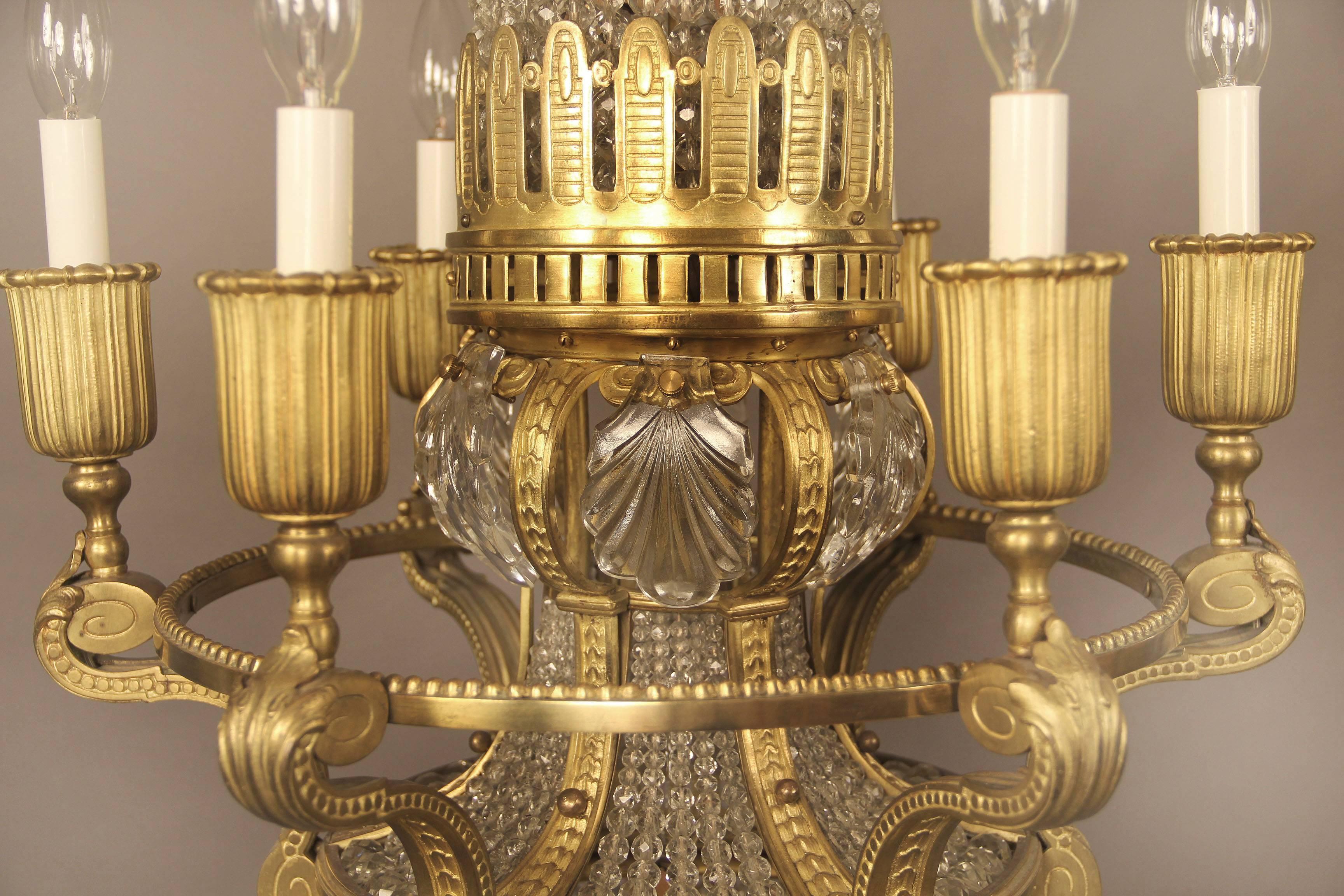 An interesting late 19th century gilt bronze and crystal ten light basket chandelier

A long and narrow beaded neck and body, bronze arms leading to six perimeter lights and four-tiered interior lights.