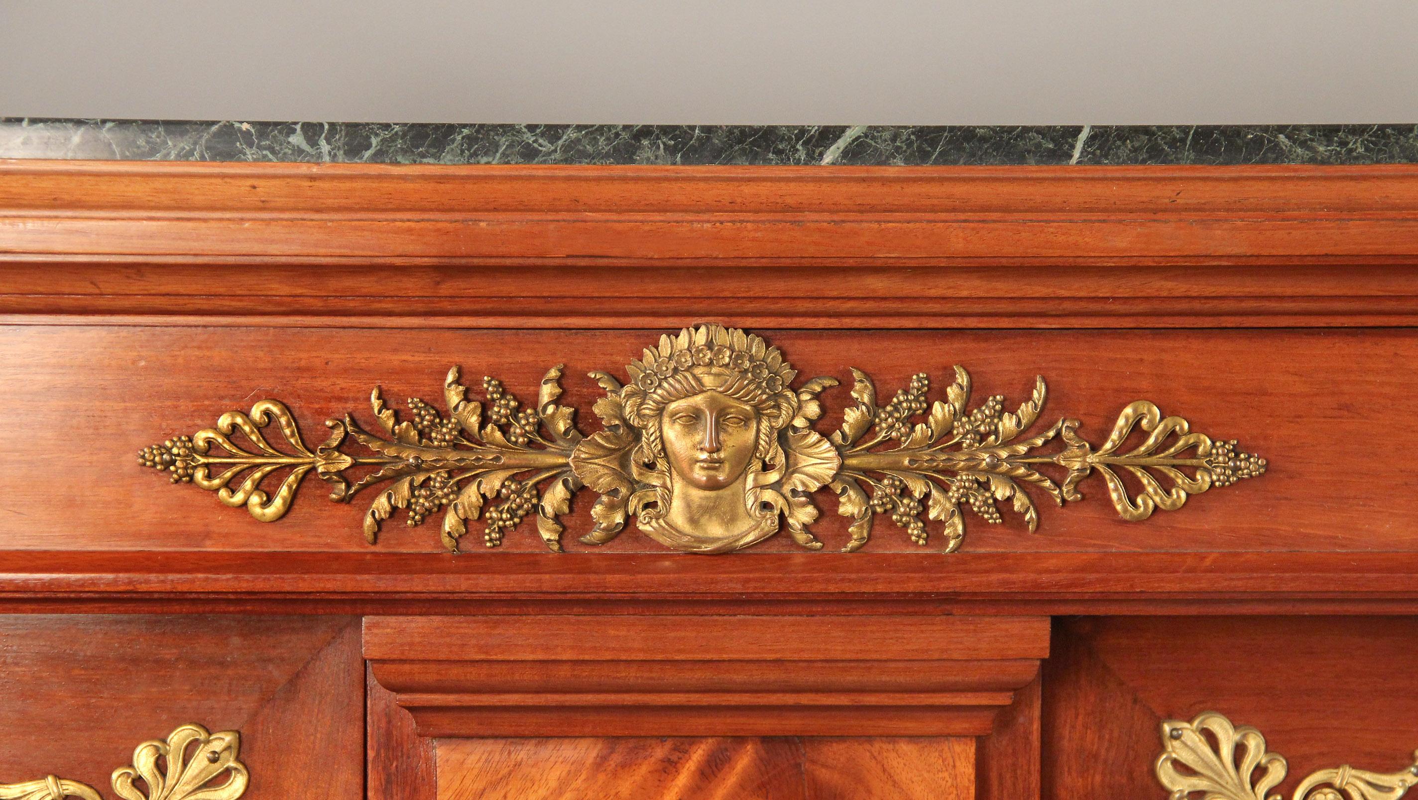 Intéressant cabinet de style Empire monté en bronze doré de la fin du XIXe siècle

Le plateau en marbre de sinople surmonte deux grandes portes ornées d'anges, le centre du plateau est décoré d'une jeune fille et les côtés de têtes de femmes. Le