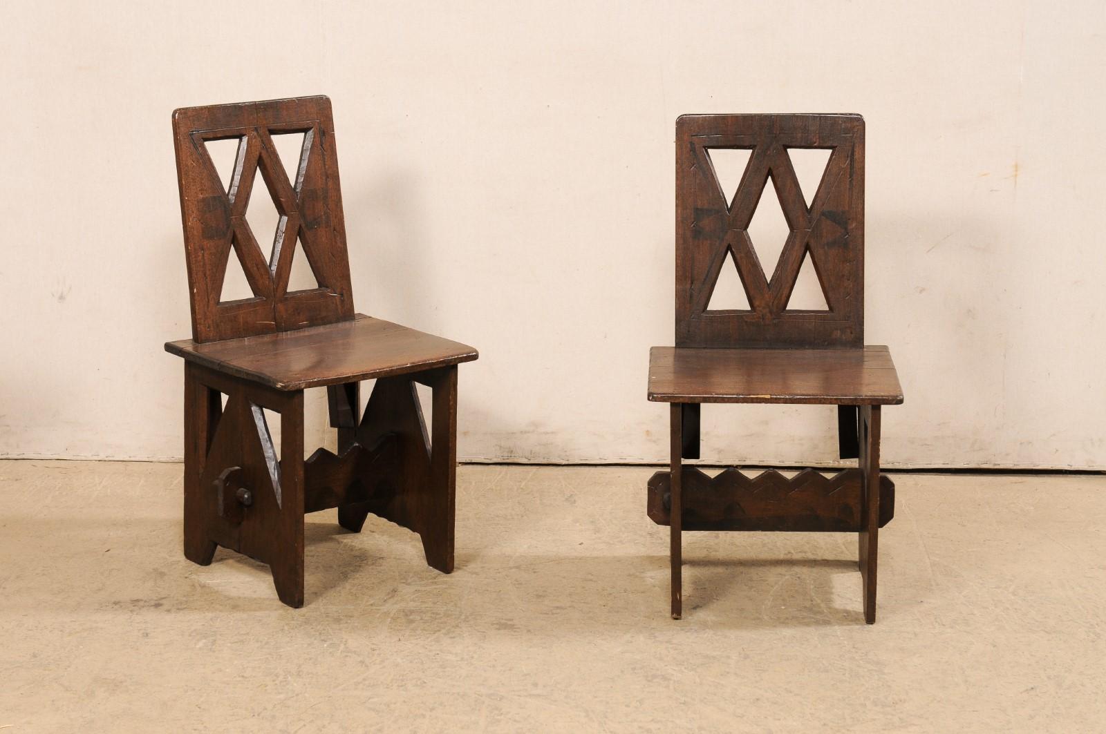 A very interesting pair of hand carved wood fireside chairs. These vintage chairs have African style carvings, and though we are unsure of their exact origin, we suspect they are N. African. The chair back rests are pierce-carved, each with a center