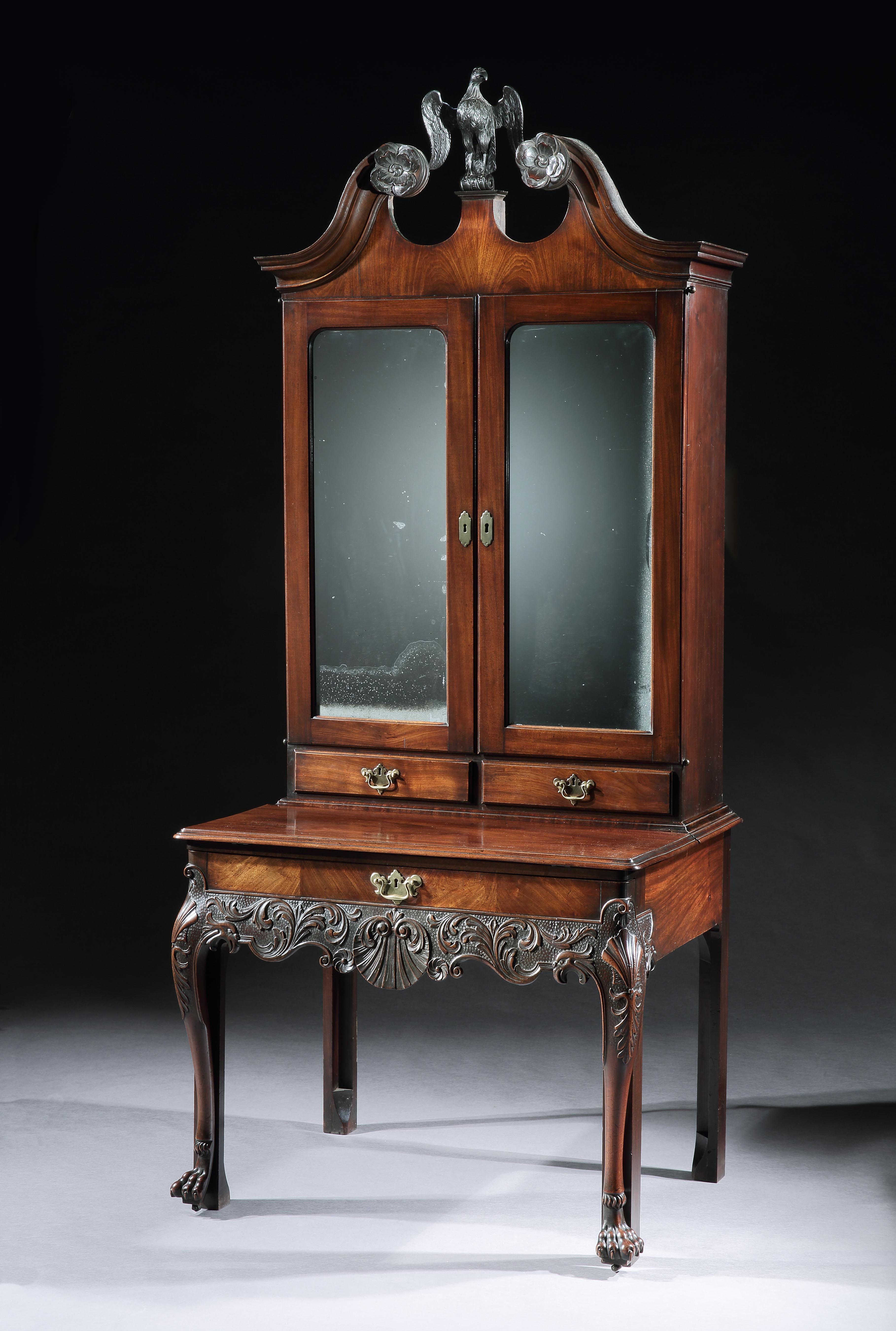 A rare and important 18th century Irish mahogany architects cabinet. The swan neck cornice, mounted with carved Irish rosettes, outside a central carved eagle, above two mirror doors, concealing a fitted interior, resting on a pull out base, fitted