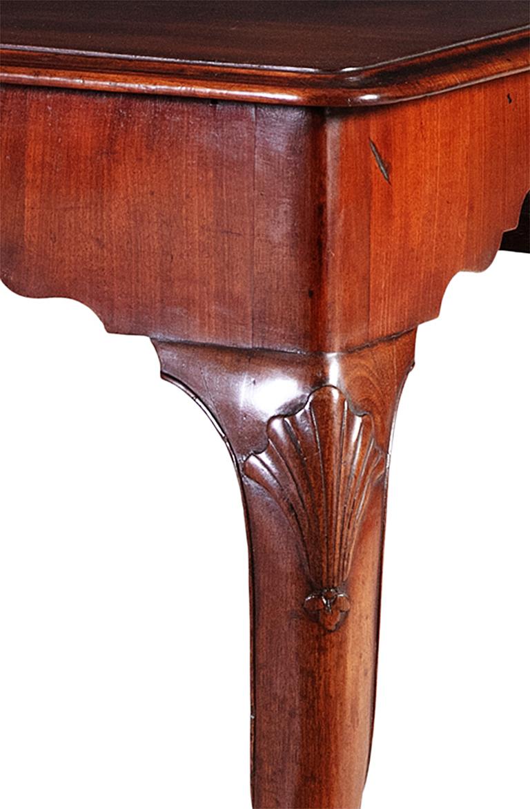 A small Irish George III mahogany console table. The figured rectangular top with a moulded edge, above a plain frieze, with a central scallop shell, resting on cabriole legs, with a faceted foot.