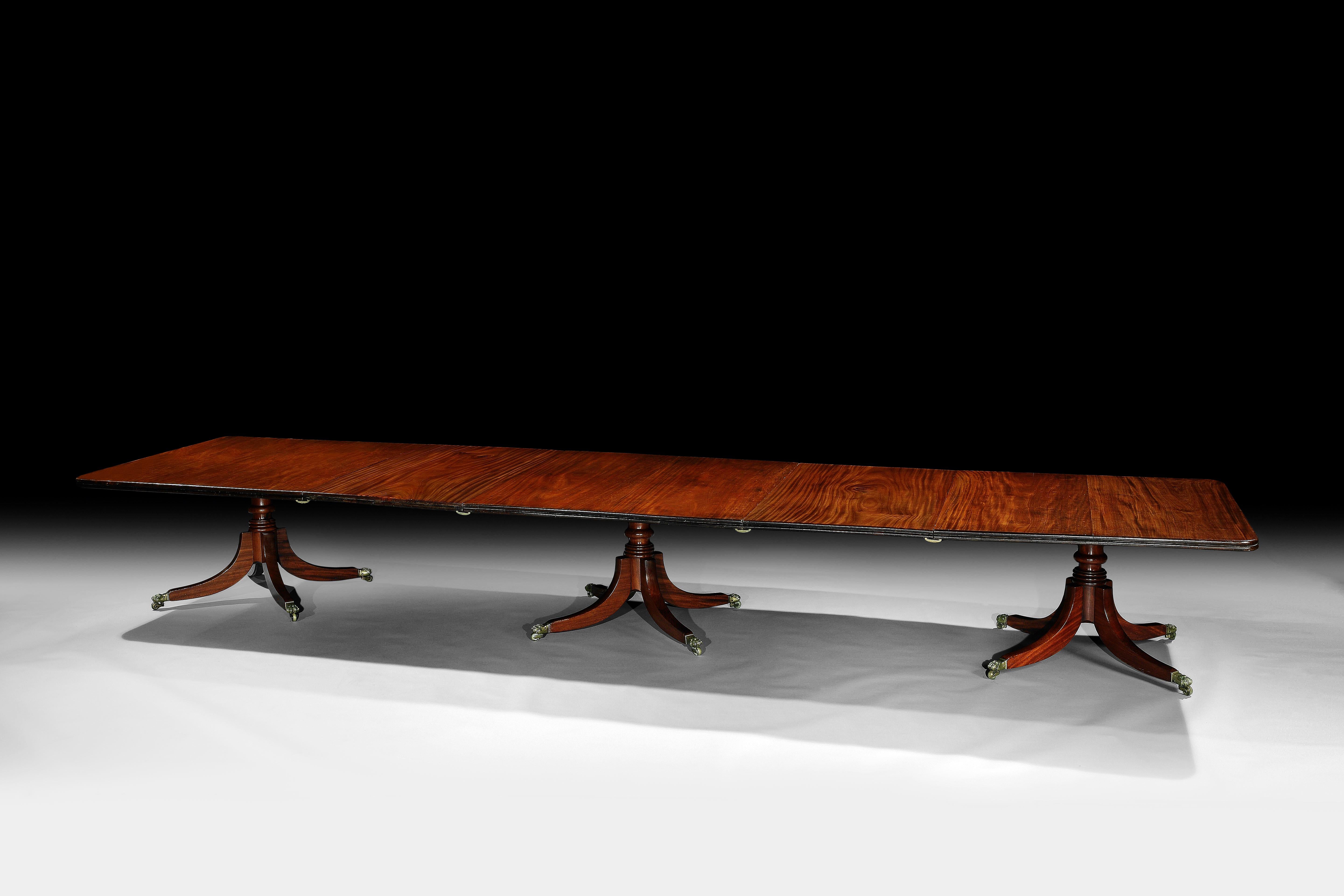An Irish George IV Figured Mahogany three pillar dining table
The rectangular top with a double moulded reeded edge, 
with two additional leaves, rested on three turned four shoot off pillars, 
with brass toed castors.
In the manner of Williams