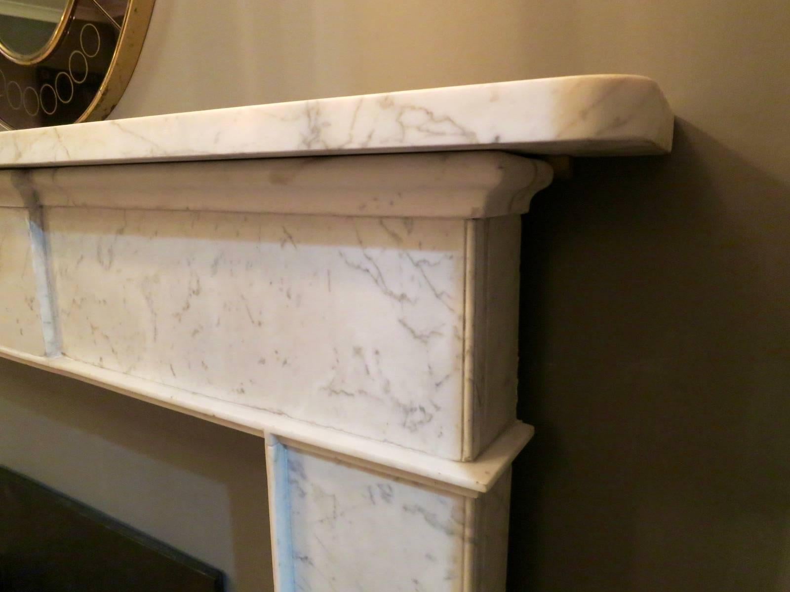 An architecturally designed George III surround in pencil vein Carrara and statuary white marbles. Supported on statuary foot blocks, with statuary in grounds, mouldings and bed moulding. The jambs, shelf and frieze in Carrara. A good example of an