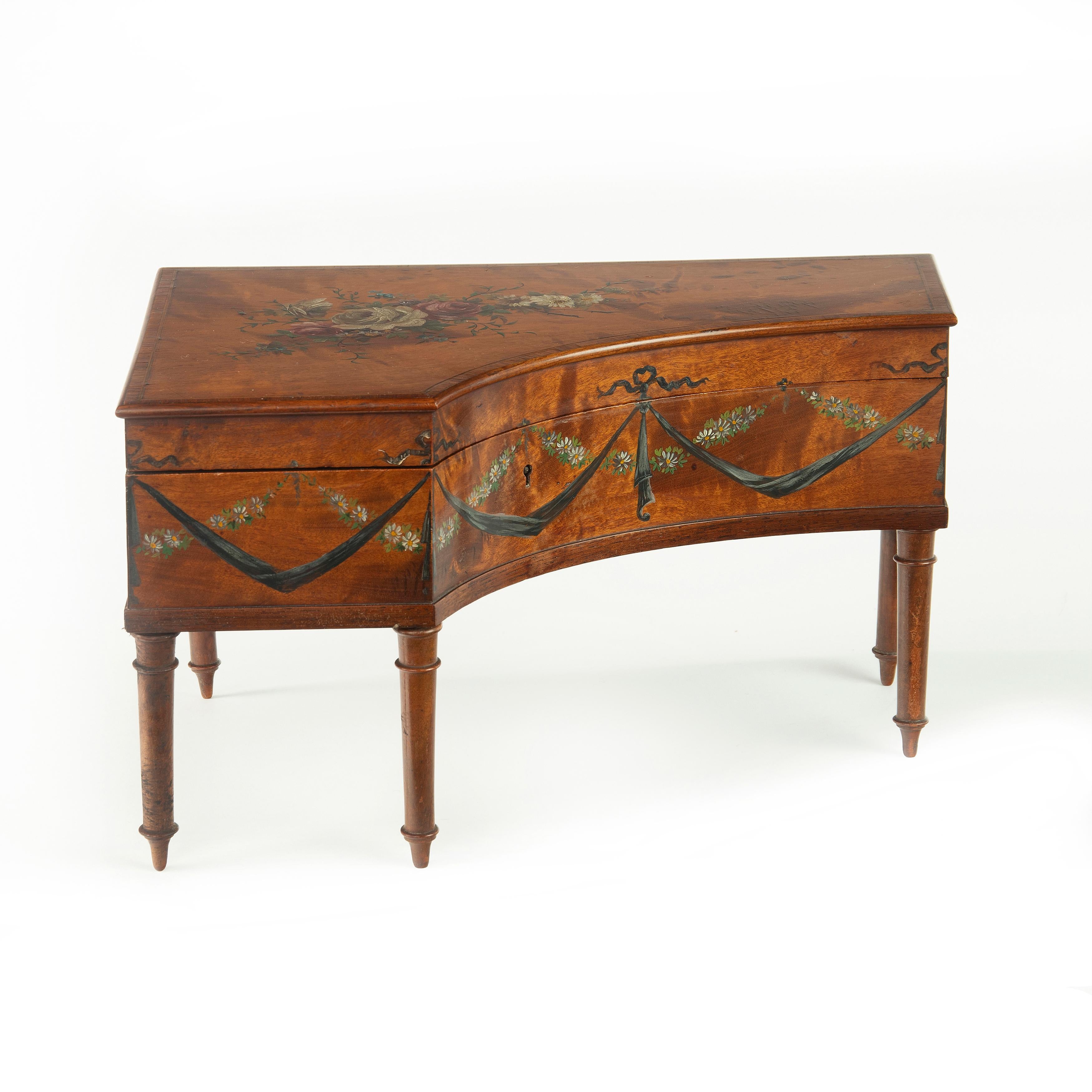 An Irish miniature satinwood piano sewing box painted by Herbert Cooper, in the form of a grand piano with a hinged lid opening to reveal a silk lined interior, decorated with a painted central spray of roses on the lid and daisy chains with