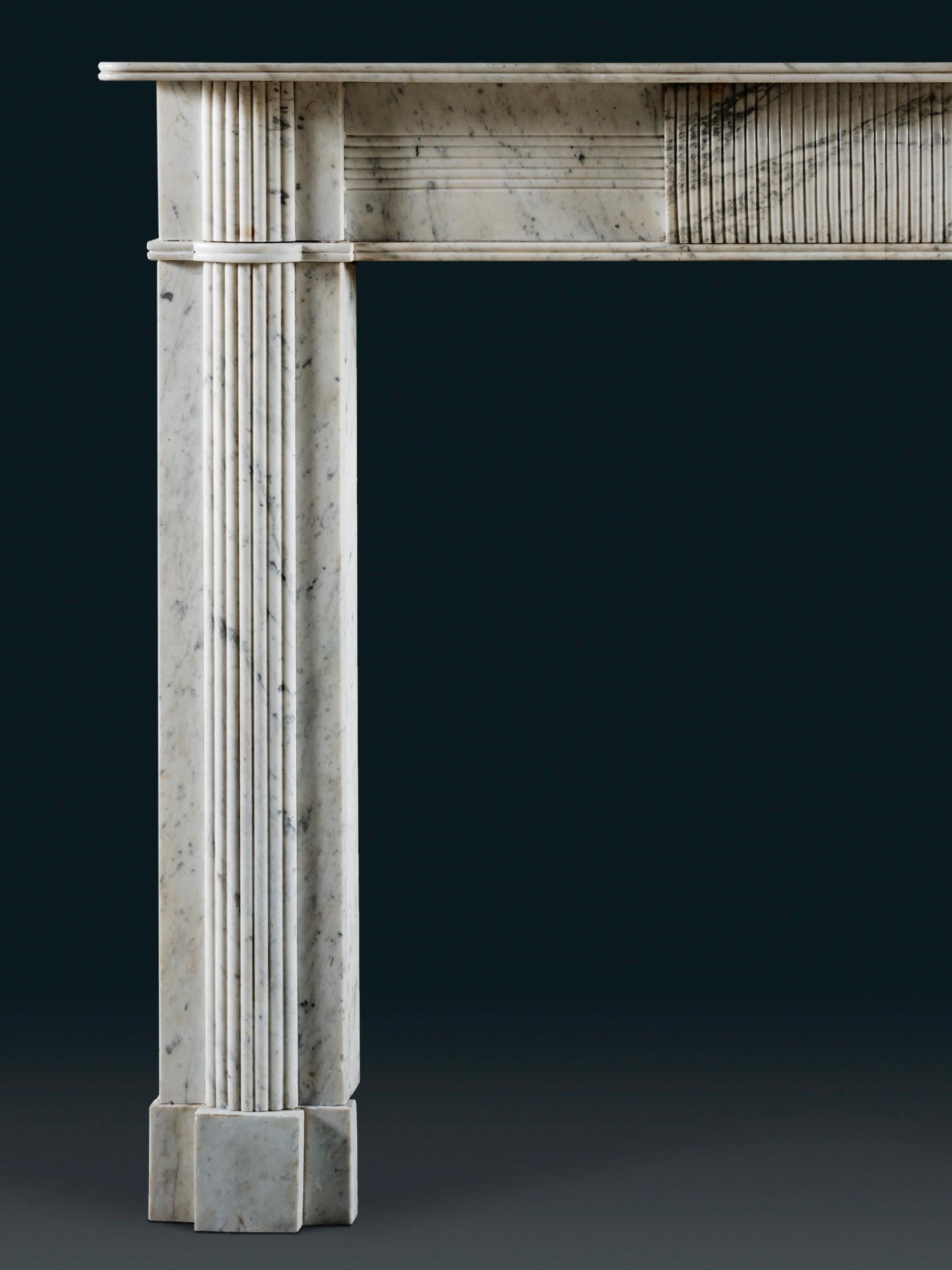 Cheminée de style Régence irlandaise, à forte cannelure, entièrement sculptée en marbre de Carrare de l'ancienne Angleterre. Une fine tablette de style Regency repose sur des montants et une frise bien proportionnés. Cette pièce est centrée sur une