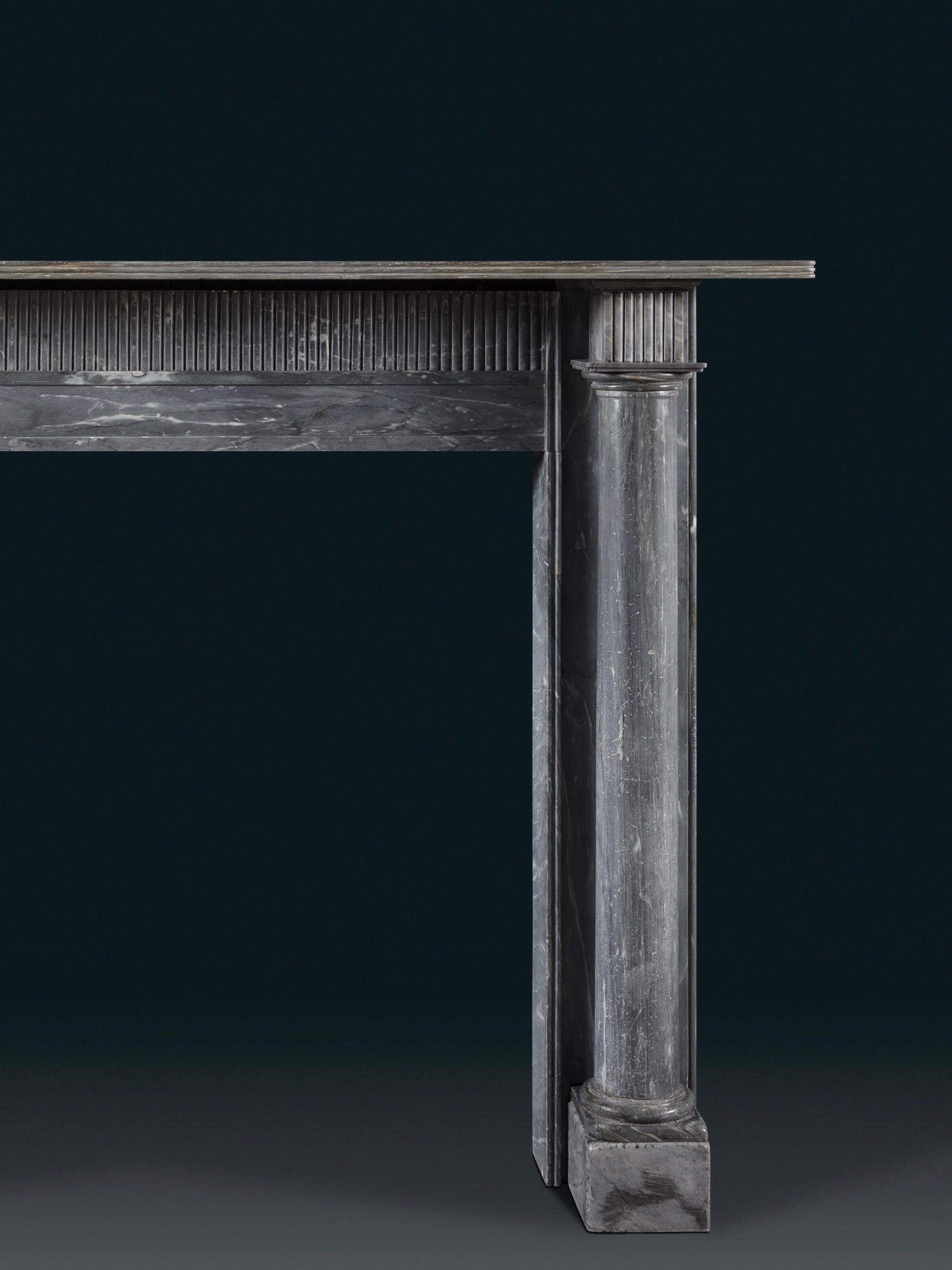 Les jambages en forme de colonnes doriques indépendantes sur des socles, reposant sur des blocs de pieds carrés. La frise est sculptée d'un motif cannelé qui s'étend sur les blocs d'angle, supportant une simple étagère moulurée. Une cheminée