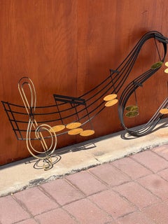 An iron and brass musical note wall sculpture by Curtis Jeré, signed, 1991