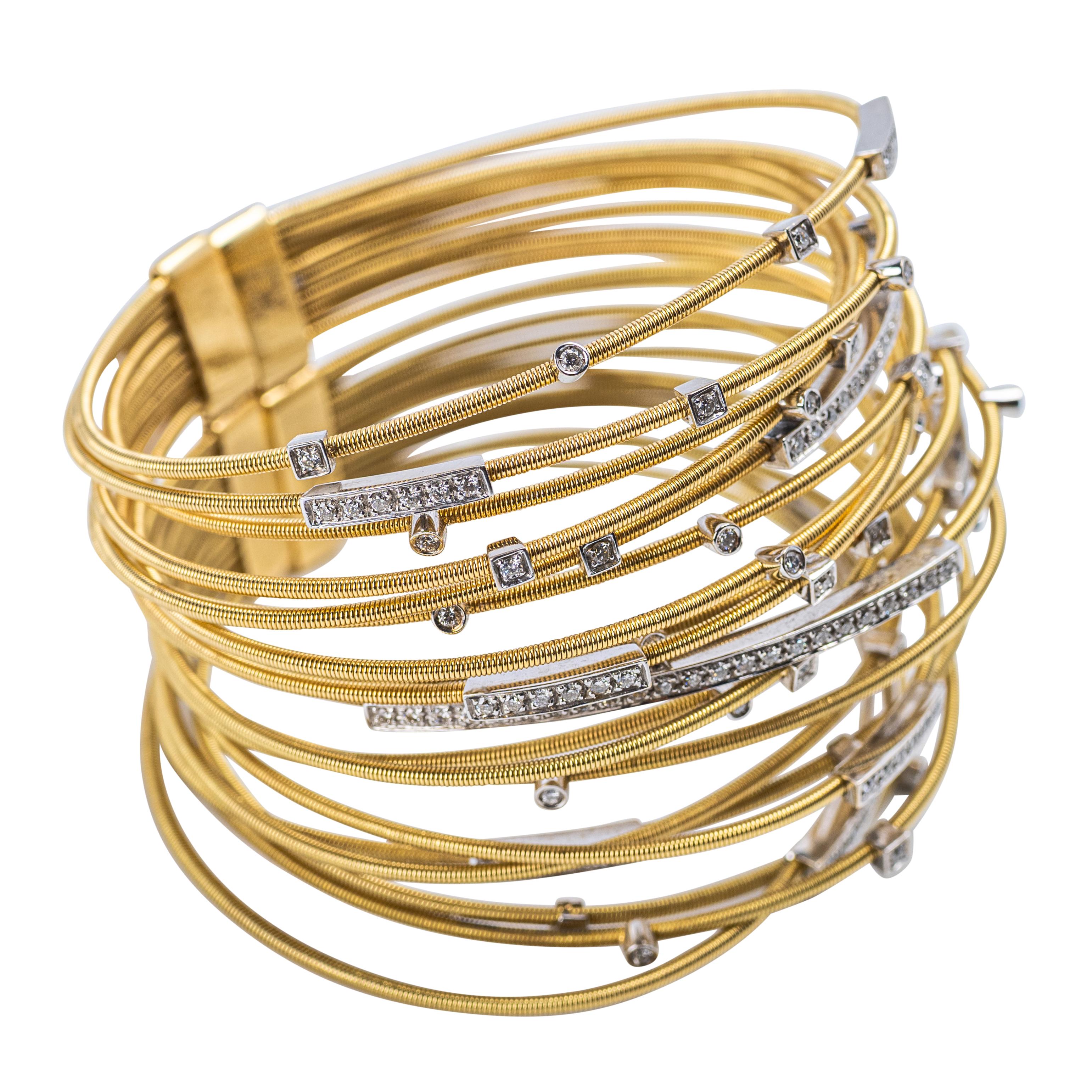This stunning Italian bracelet features nineteen coiled 18K yellow gold bands accented with white gold and diamond details. Pavé-set diamond bars and bezel-set round diamonds add sparkle and texture throughout. Expertly crafted and stamped 18 Kt