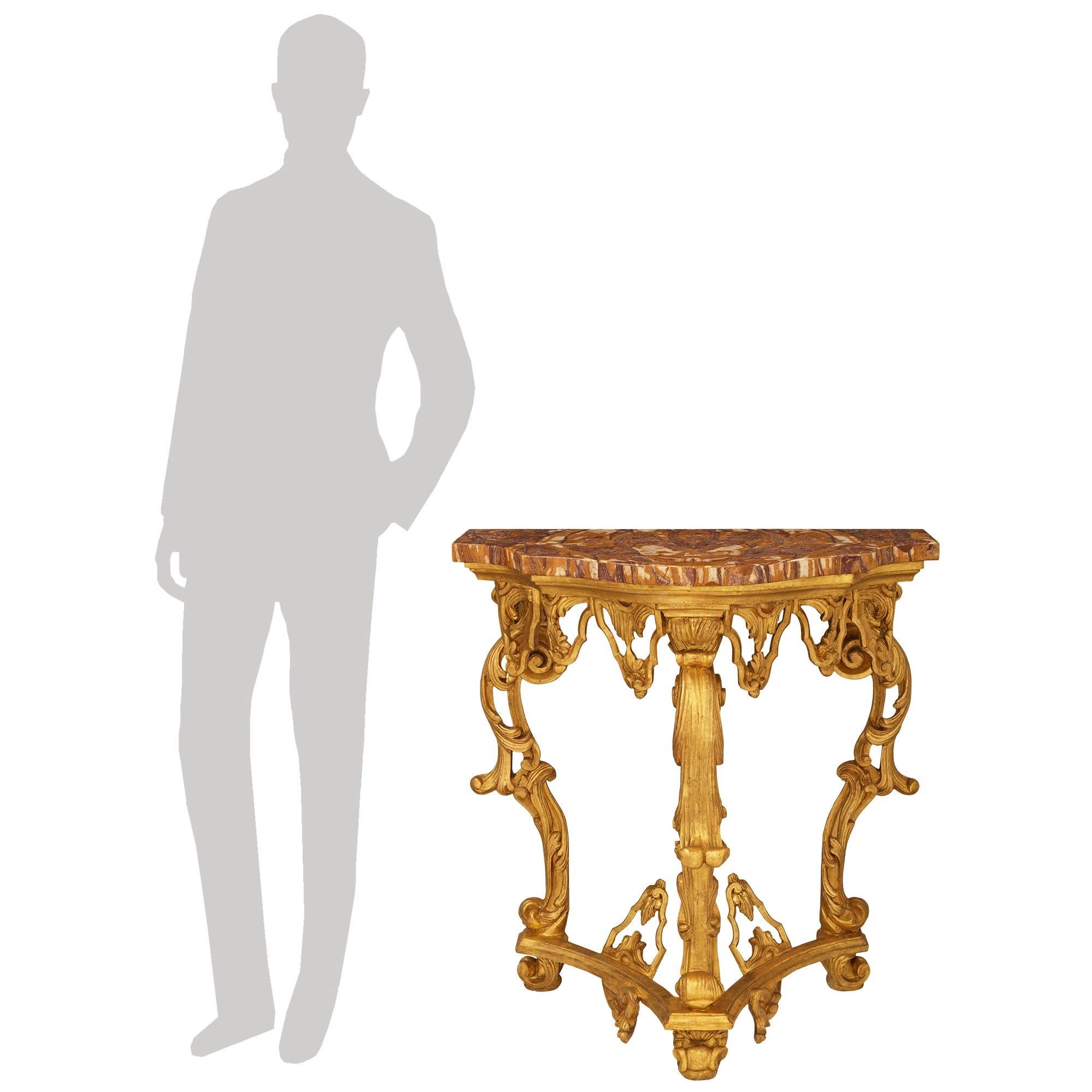 Un'imponente console italiana del XVIII secolo in legno dorato e marmo Alabastro Rosso. Questa eccezionale console indipendente è sollevata da un Trio di piedi intagliati a foglie d'acanto sotto una barella decorata con riserve di fogliame e
