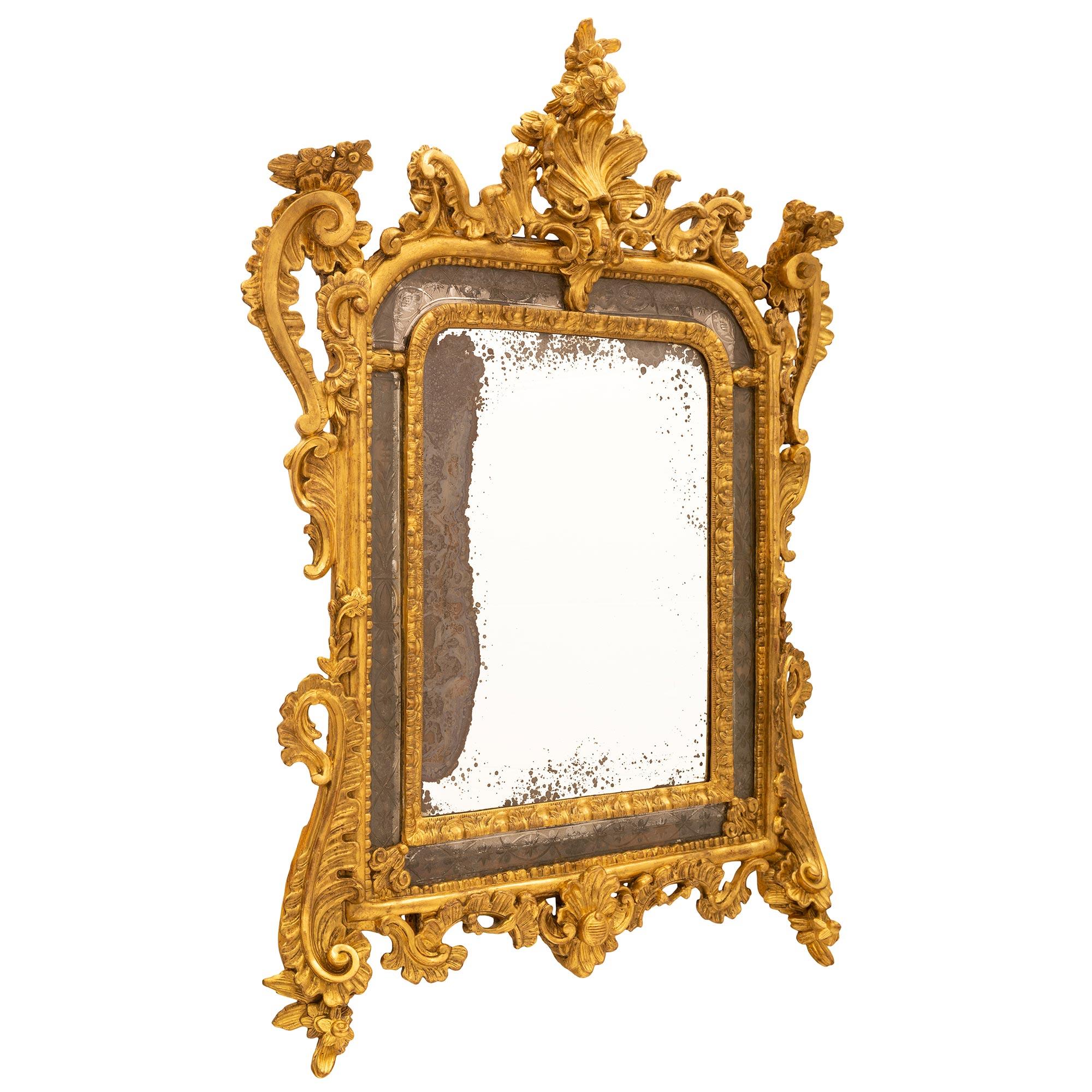 Remarquable miroir en bois doré à double encadrement, de style baroque italien du XVIIIe siècle. Le miroir a conservé toutes ses plaques d'origine, la plaque centrale étant encadrée d'une bordure feuillagée finement sculptée et les plaques