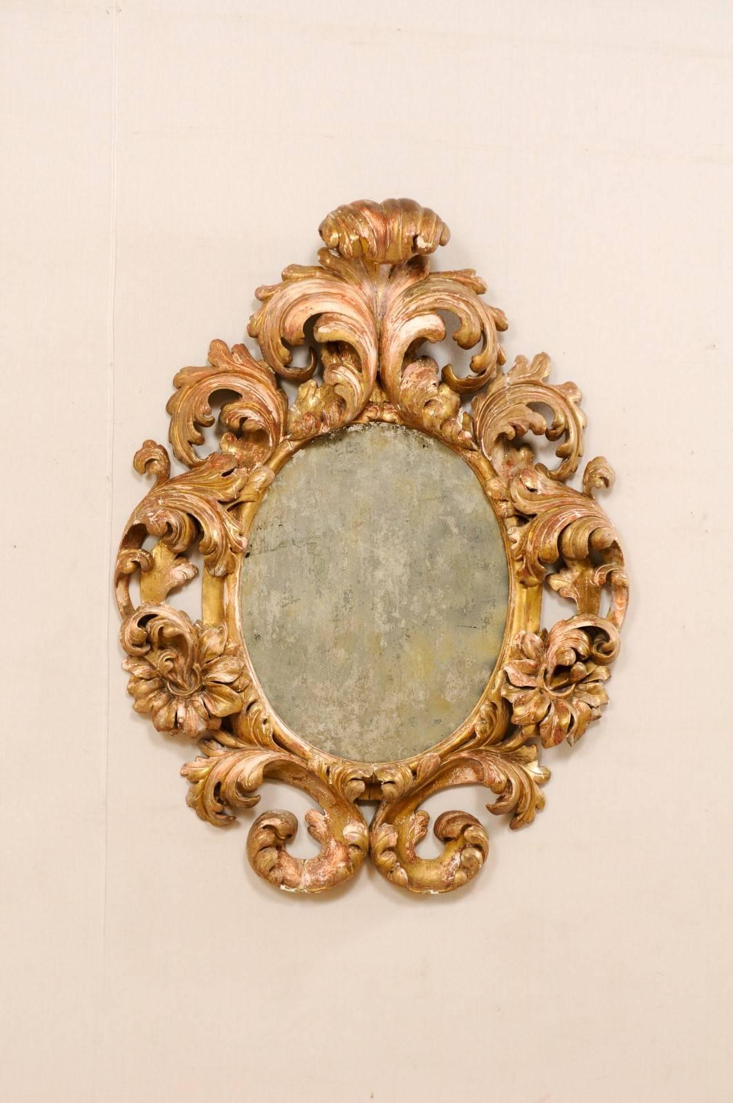 An Italian 18th century carved acanthus leaf mirror. This elaborate antique Italian mirror, circa 1740, features a richly carved ornate acanthus leaf surround with an oblong, oval shape. The carved details are spectacular, the scrolling leaves are