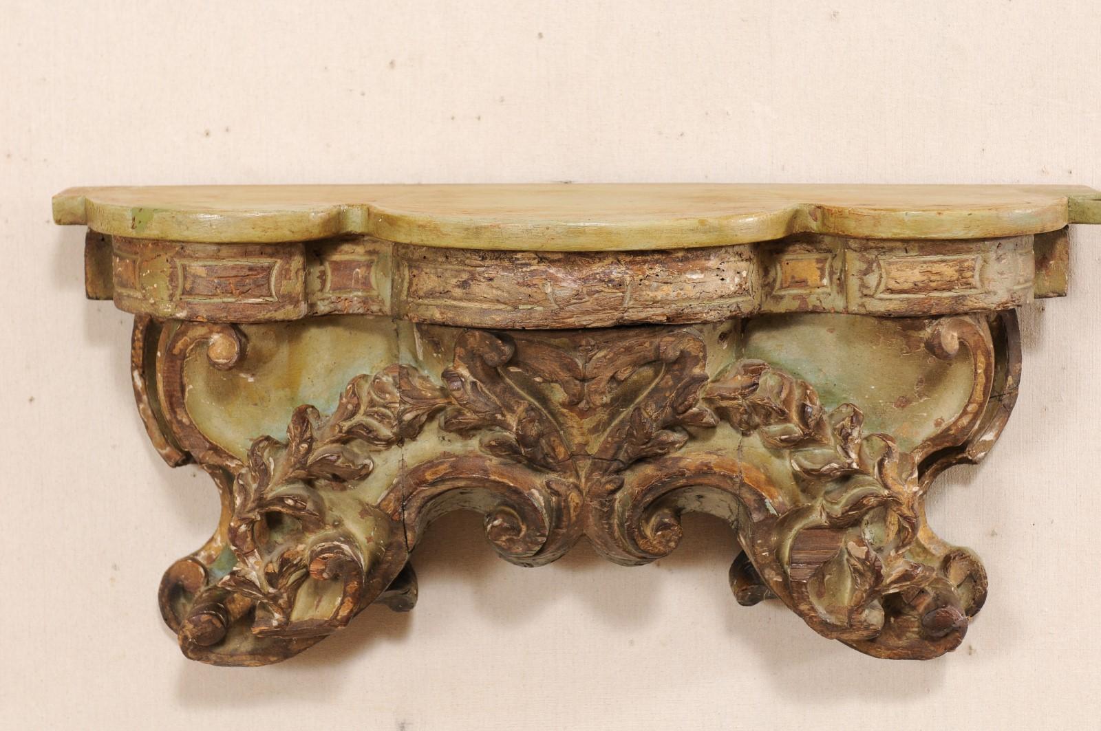 An Italian ornately carved wood fragment wall-shelf from the 18th century. This antique wall decoration from Italy features a beautifully hand carved wood fragment, rich with leaf and scrolling motif, which has at some point had a newer addition of