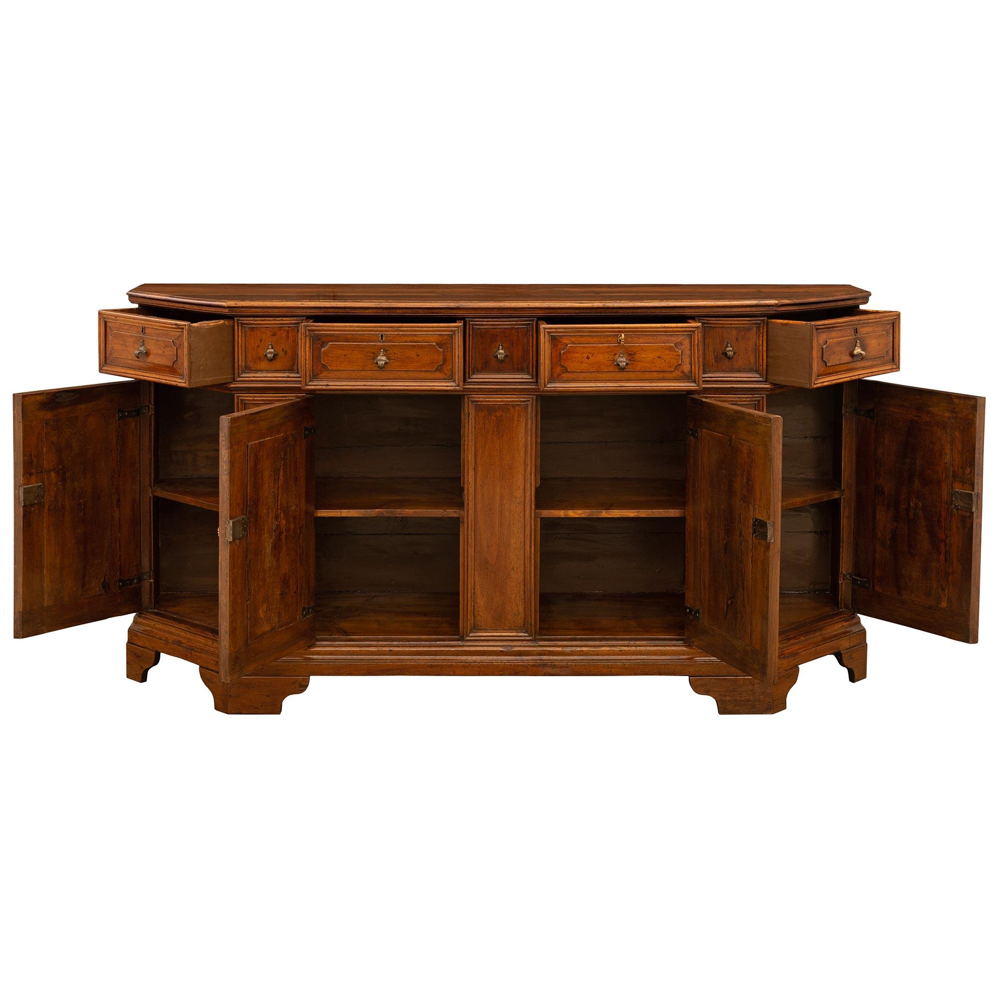A handsome and very attractive Italian 18th century Walnut buffet, from Tuscany. This wonderful four drawer four door buffet with its original hardware is supported on six scallop shaped Walnut feet. Above the mottled edge straight front apron are