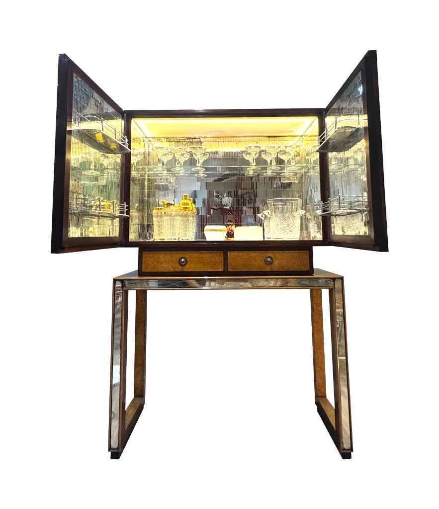 A wonderful Italian 1940s, birds eye maple and ribbon mahogany mirrored fronted bar cabinet by Osvaldo Borsani with etched designs of dolphins and flowers on the 8 mirrored panels.
The two doors open to reveal a mosaic mirrored interior, with two