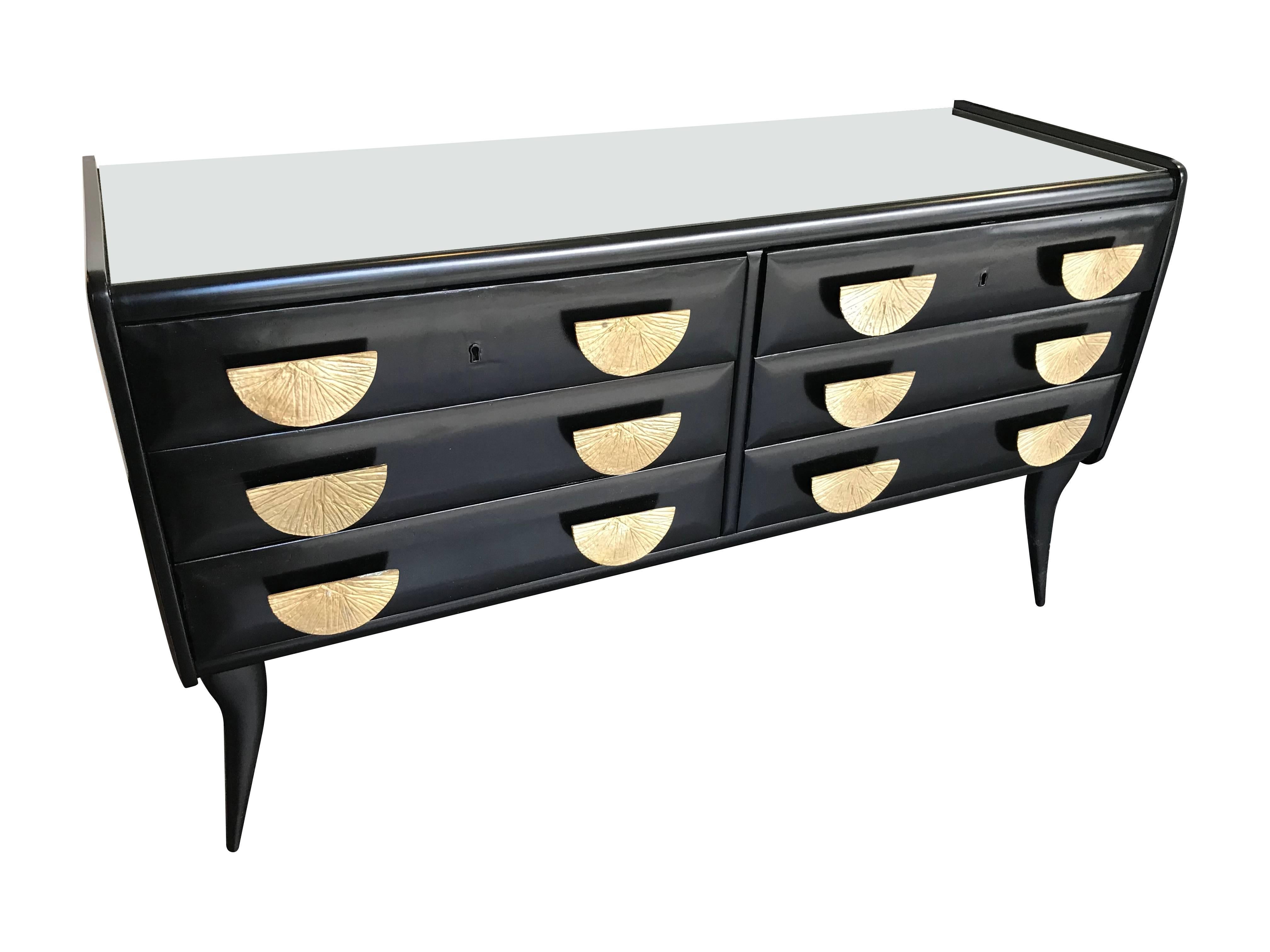 An Italian 1950s ebonised chest of drawers with six drawers, each with two brass, cast handles. With full mirrored top.