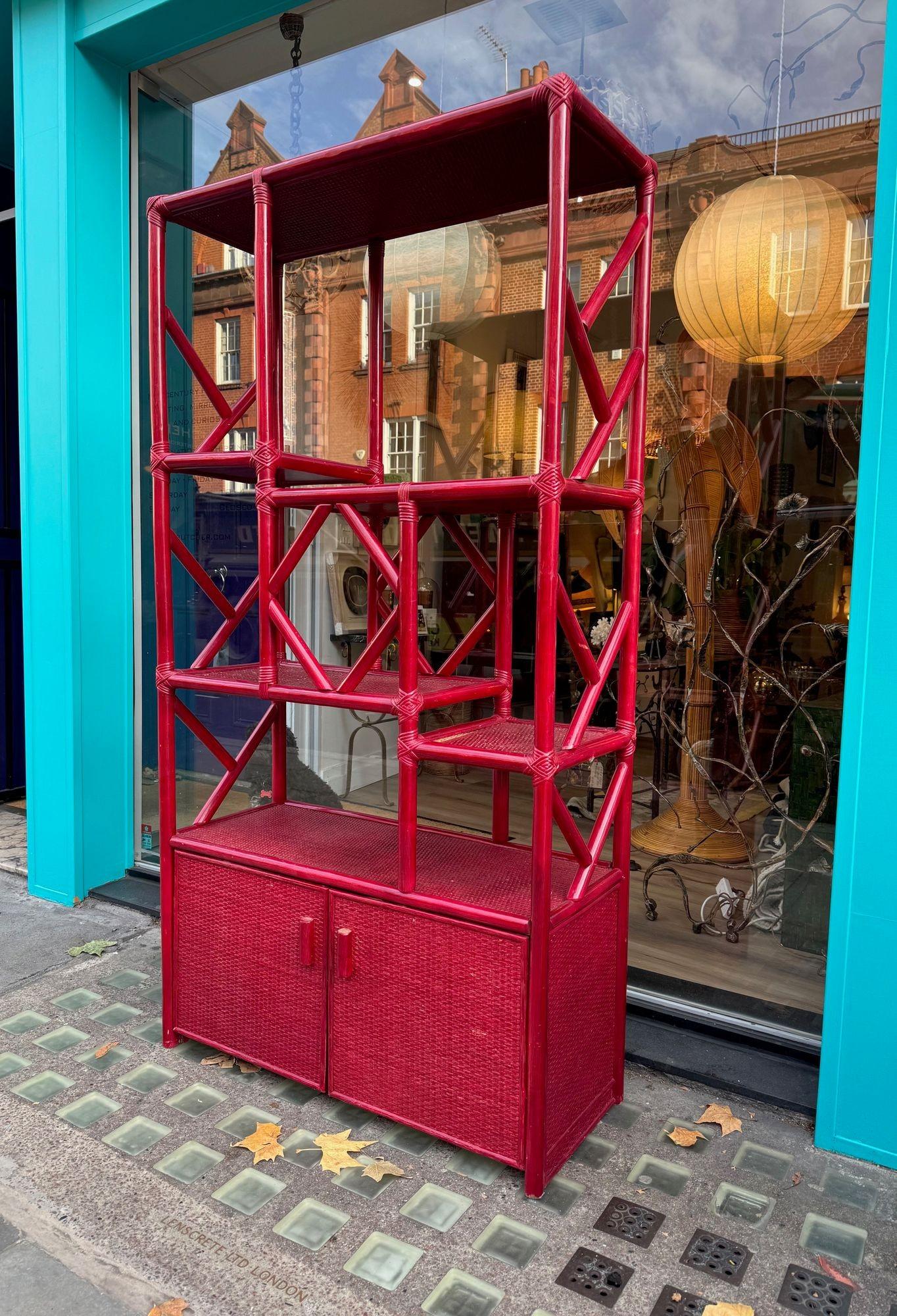 An Italian 1970s burgundy red bamboo shelving unit by Vivai del Sud, with five rattan covered shelves above a 2 door cupboard, with rattan front. 