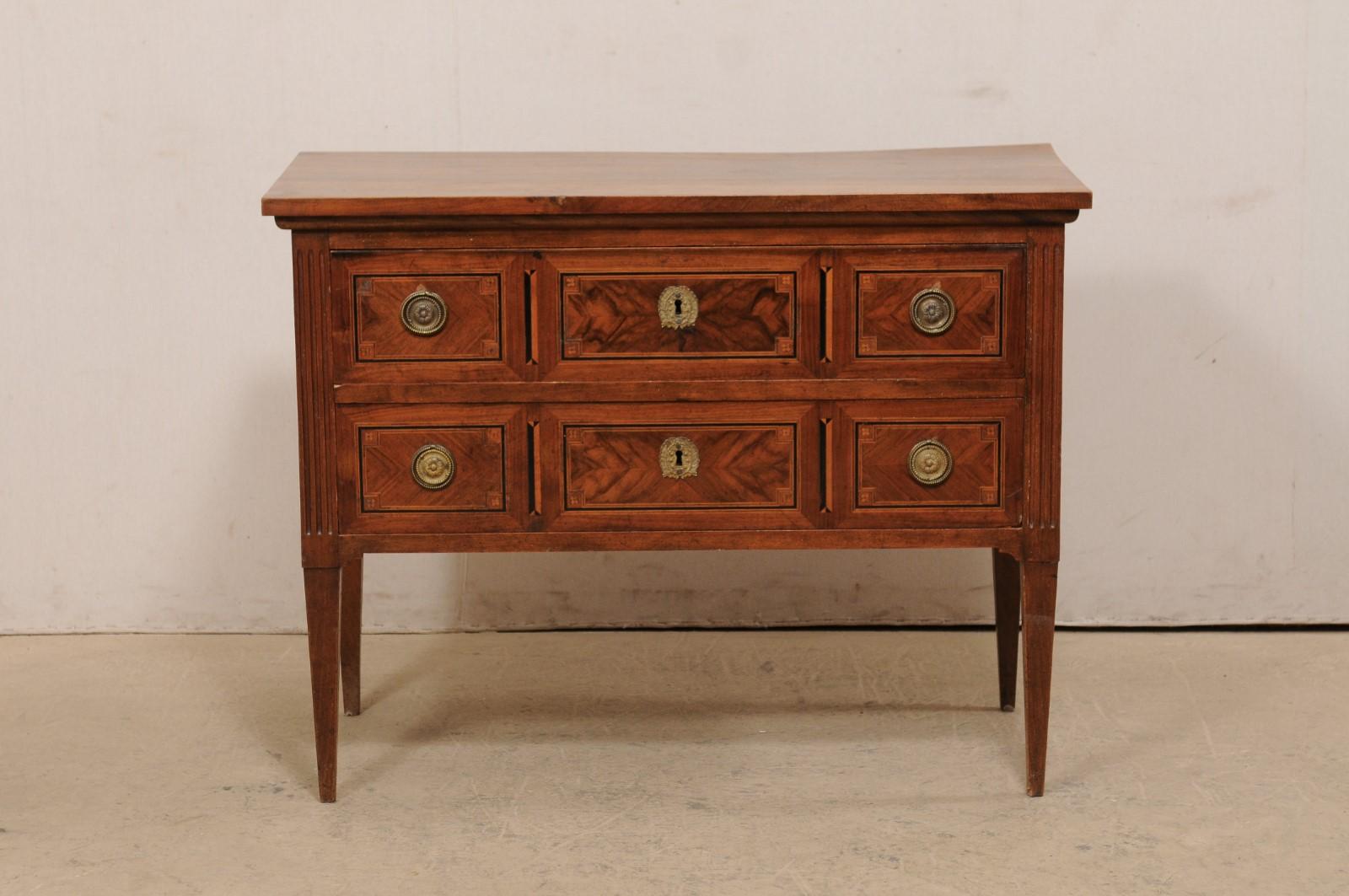 An Italian raised two-drawer chest with decorative inlay from the 19th century. This antique commode from Italy features a rectangular-shaped top with beautiful graining, atop a case which houses two drawers fitted with neoclassical style pulls, and