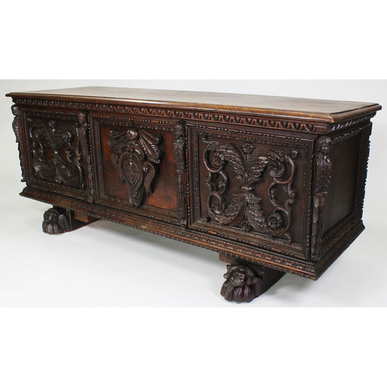 An Italian 19th century Baroque Revival style carved walnut figural Cassone chest-trunk. The ornately carved chest, also known as a marriage chest, with an opening top supported with wrought iron hinges, the front centered with a crest and