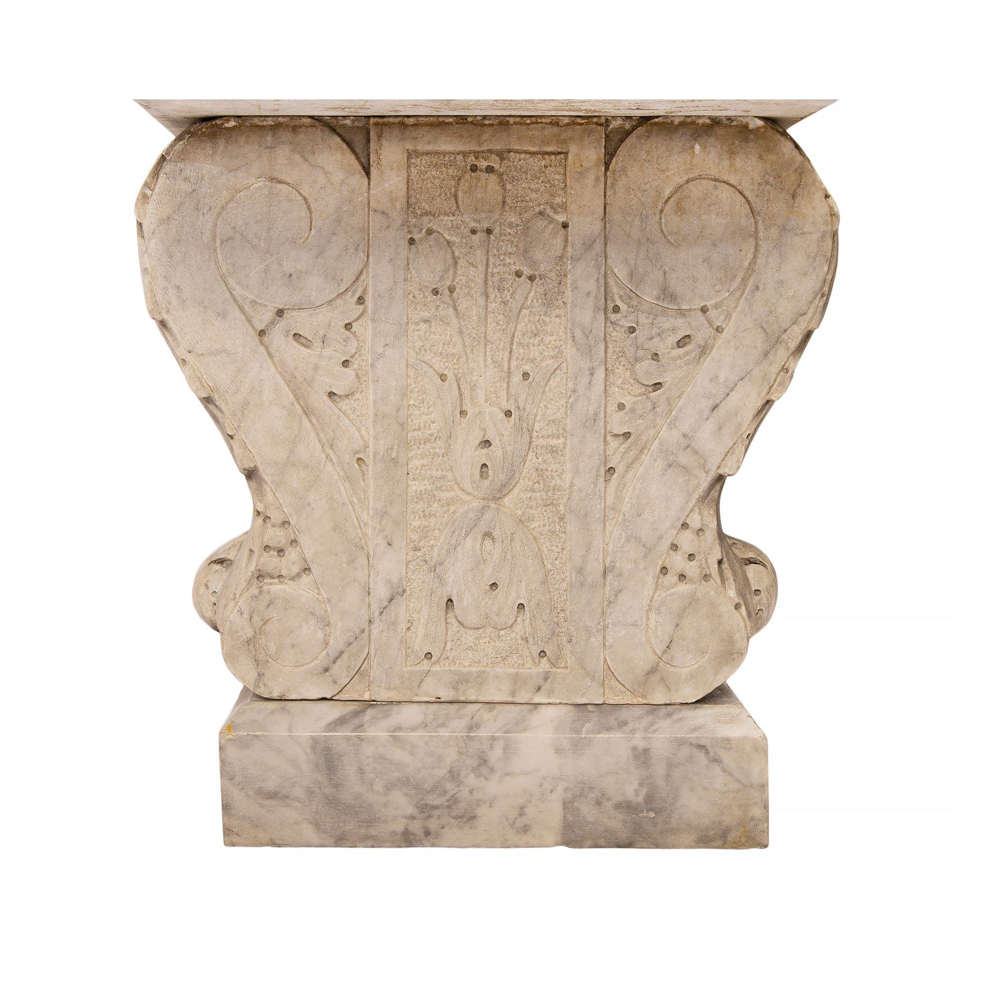 An attractive Italian 19th century Louis XV st. white Carrara marble garden bench. The bench is raised by supports above rectangular cut angled blocks. The carved supports have a scrolled design with finely carved outer acanthus leaves. The