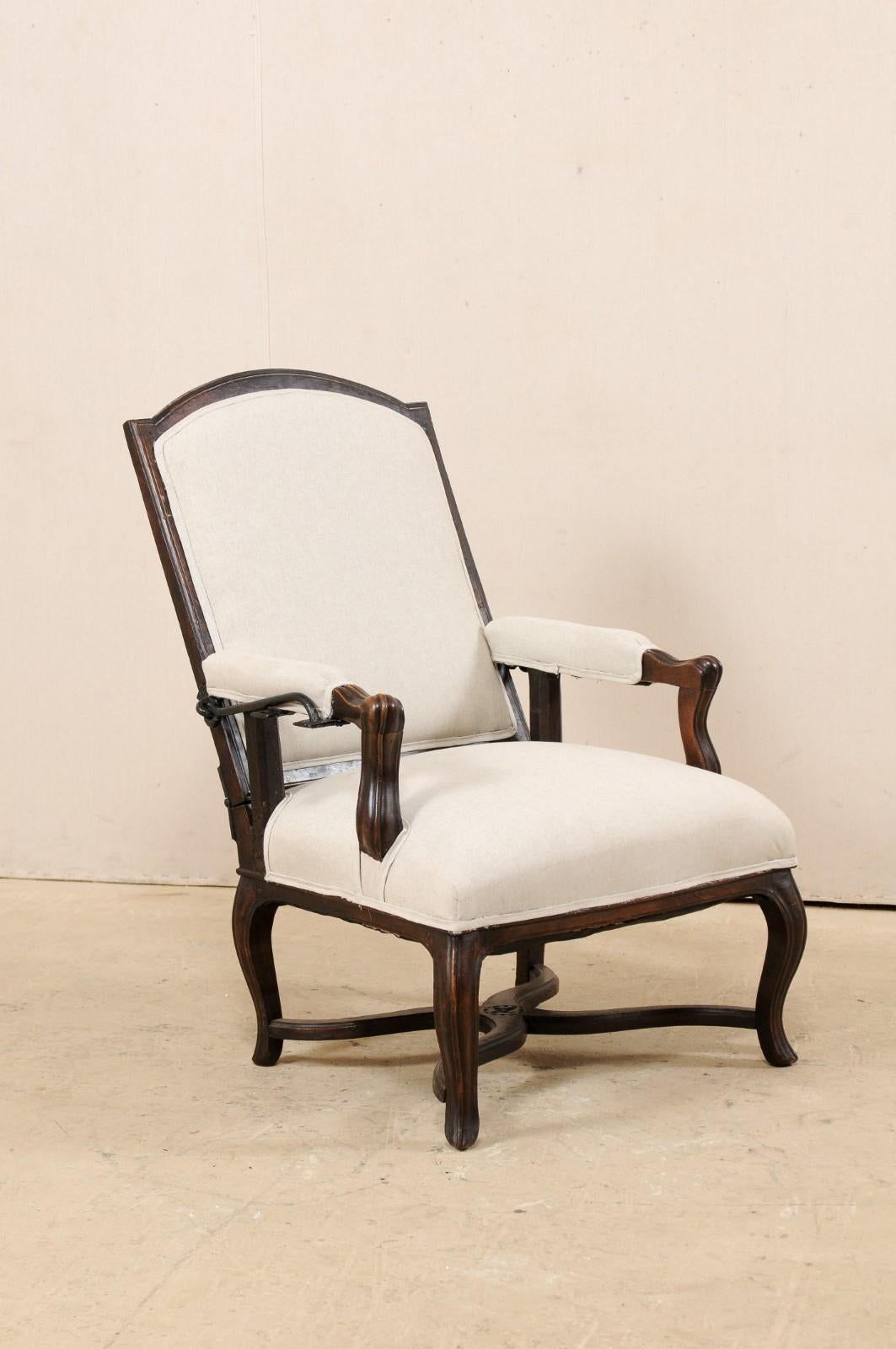 An Italian reclining wood and upholstered chair from the early 19th century. This antique chair from Italy has a rectangular-shaped back with wood arched top rail, nicely carved knuckles, manchette arm rests, and are raised upon sweetly curved legs