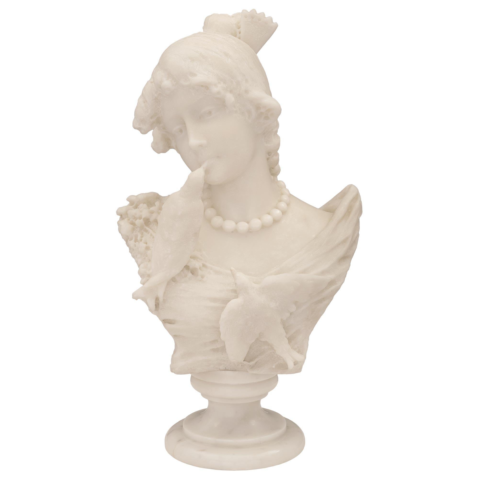 A stunning and extremely high quality Italian 19th century white Carrara marble bust of a young girl with birds. The bust is raised by a circular socle shaped pedestal support with elegant wrap around mottled bands. The wonderfully executed bust