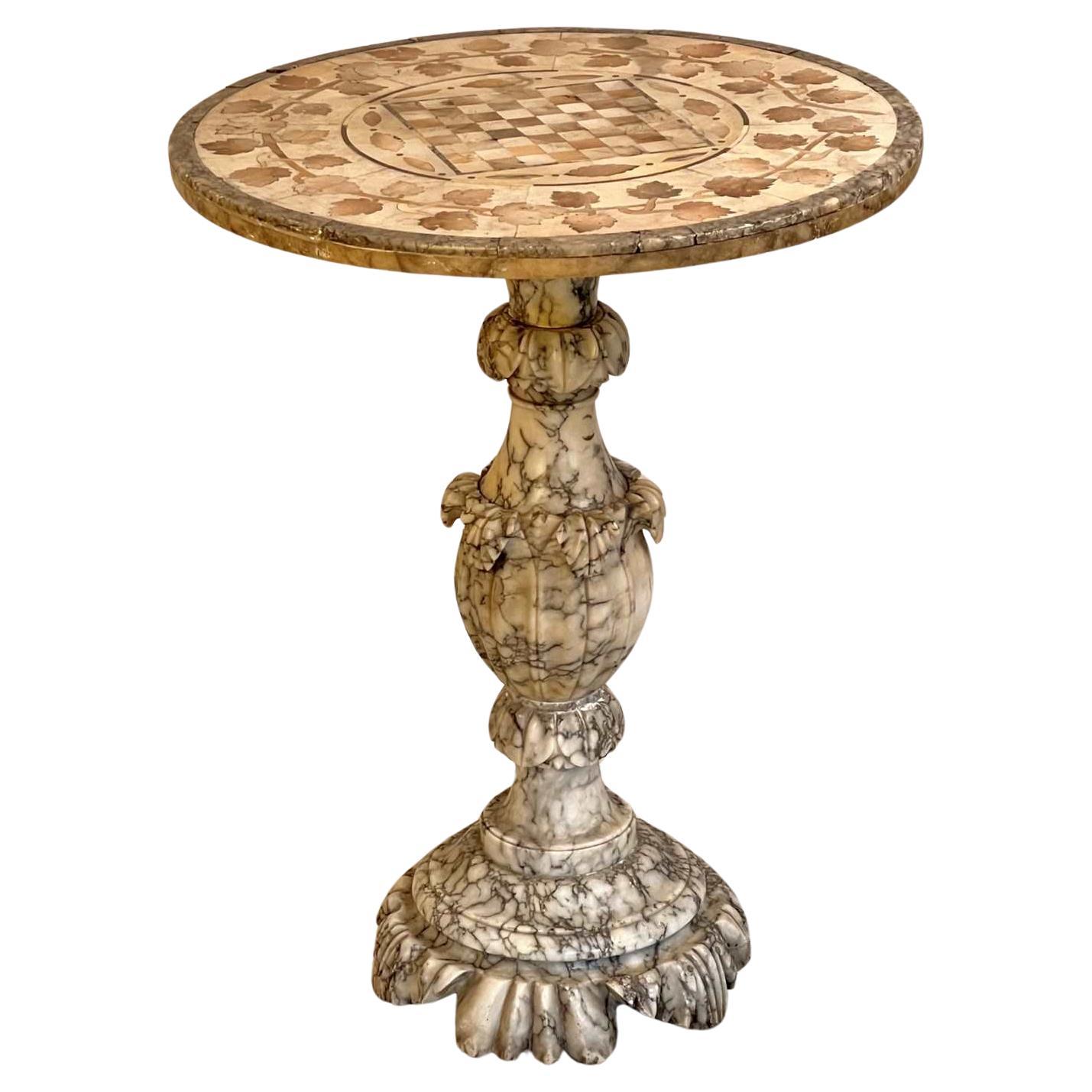 Très belle table à vin et à jeux en albâtre d'époque italienne, circa 1900. Le plateau circulaire est orné d'un décor incrusté de feuilles de vigne sur son pourtour et d'albâtre contrastant sur sa lèvre. Le damier central est entouré d'un cercle à