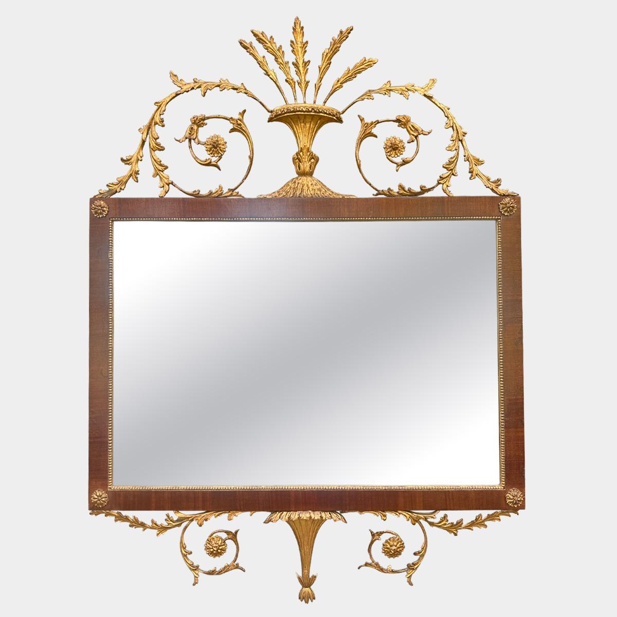 Specchio italiano di fine o inizio XX secolo in legno intagliato e dorato. Frontone decorato in modo elaborato con grandi acanti e rosette a volute, centrato da un'urna con esplosione fogliare. La cornice è in legno scuro e ricco, con rosette dorate