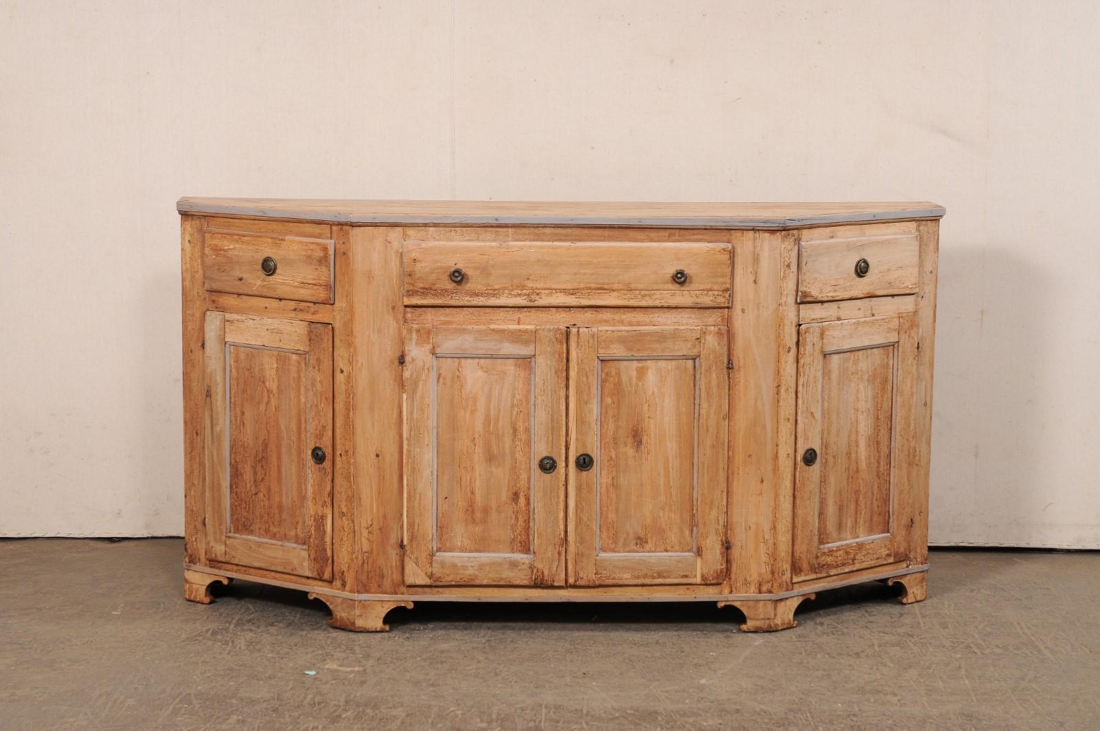 Una credenza italiana in legno degli inizi del XIX secolo. Questo antico buffet italiano ha un piano angolare a forma di demi, con una parte anteriore più corta e dritta affiancata da estremità a sbalzo e una parte posteriore più lunga. Ci sono tre