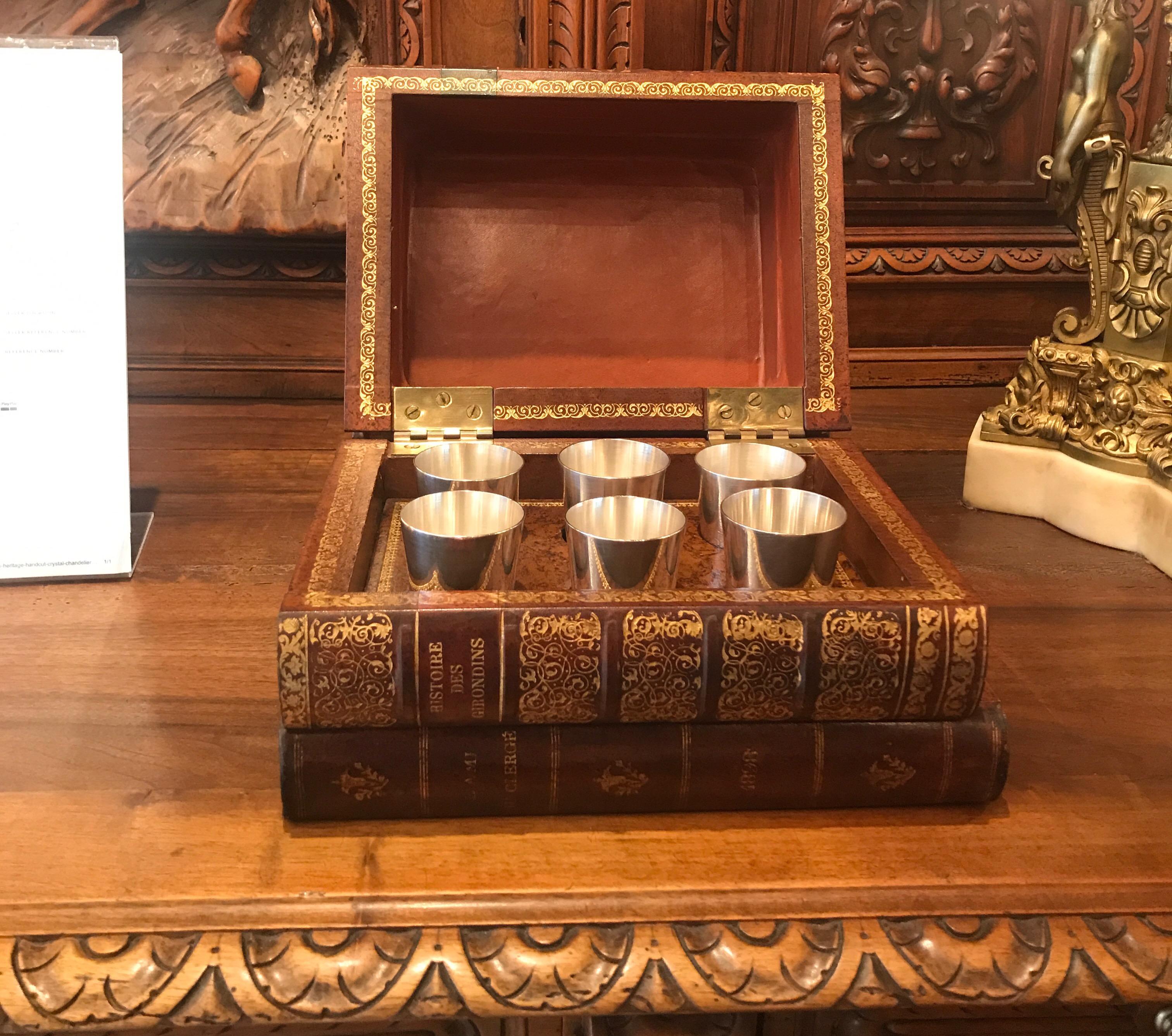 An Italian leather book box with six silver plate tumblers. The box in the form of a sack of four books with six engine turned engraved small tumblers.