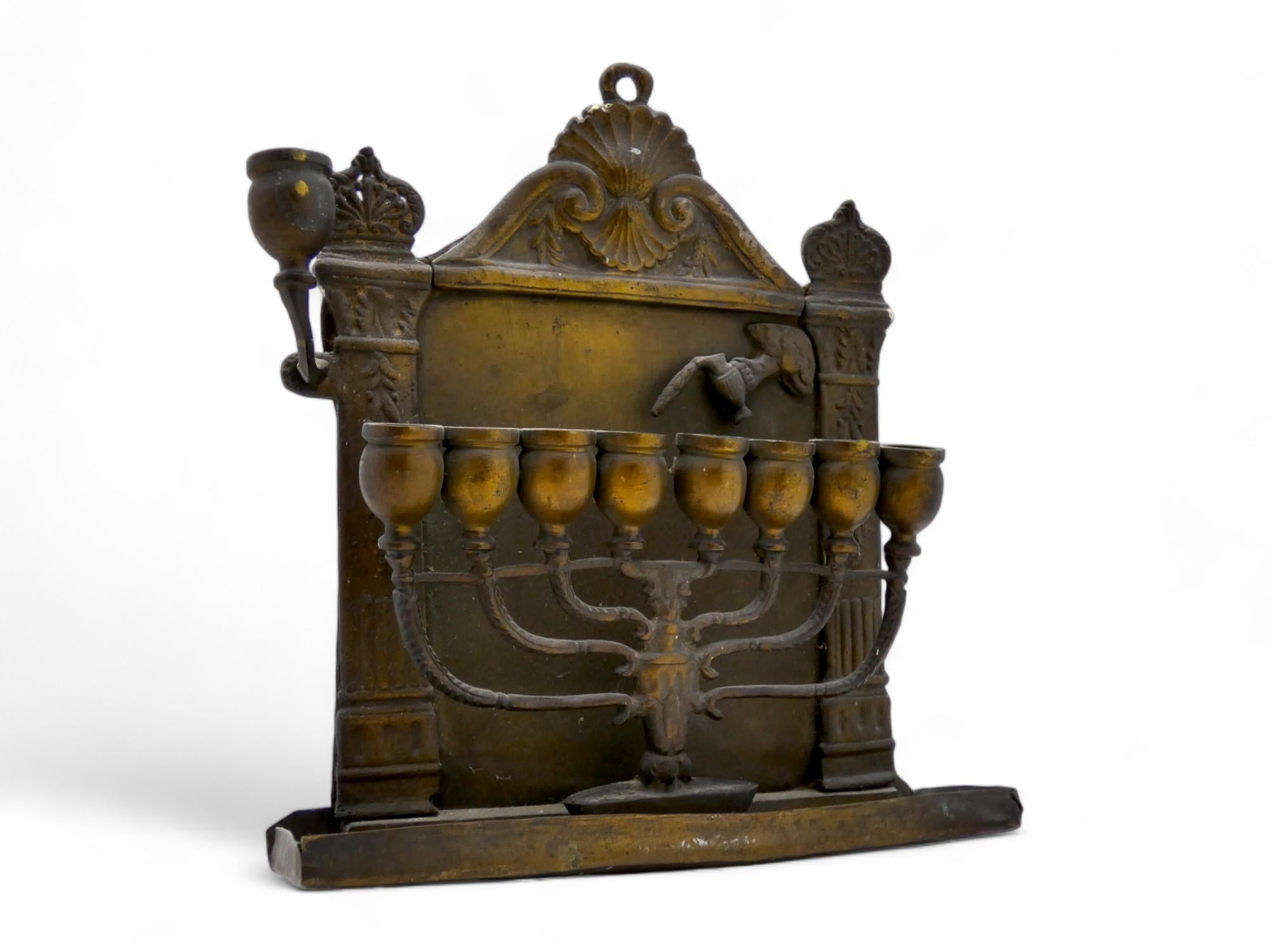 Un'interessante lampada Hanukkah Menorah italiana in ottone realizzata in modo unico intorno al 1800.

La lampada di Hanukkah è attaccata alla parte inferiore della piastra posteriore e ha la forma di una menorah completamente formata con otto vasi