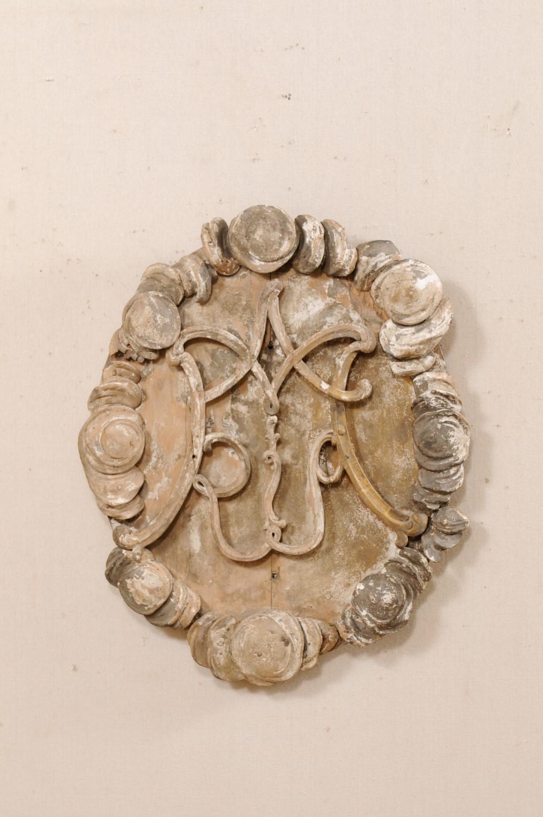An Italian carved wood fragment wall ornament from the 19th century. This antique wall plaque from Italy has a mostly oval-shape and has been hand-carved with thick, raised perimeter carvings and a stylized center. This piece retains it's original