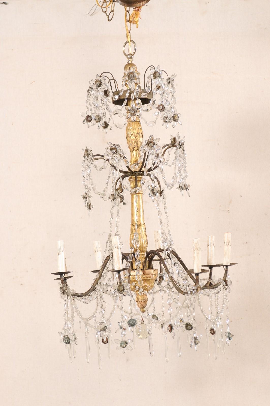 Lustre circulaire italien à huit lumières en cristal et colonne dorée. Ce lustre vintage italien se compose d'une colonne centrale en bois, joliment sculptée d'un motif de feuilles d'acanthe et d'une garniture perlée sur tout le corps, d'où émerge