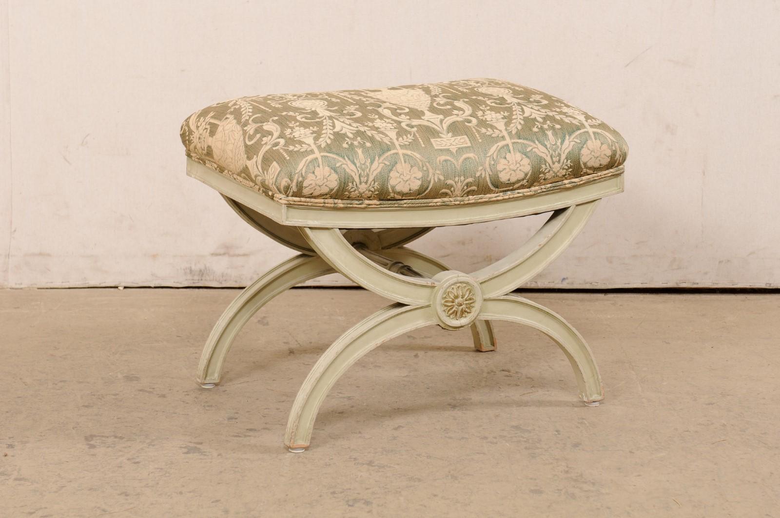 An Italian painted wood stool with upholstered seat from the mid 20th century. This vintage stool from Italy has been created in the Curule (or often referred to as Dante) style, featuring legs comprised of two half-moon shapes, which attach at