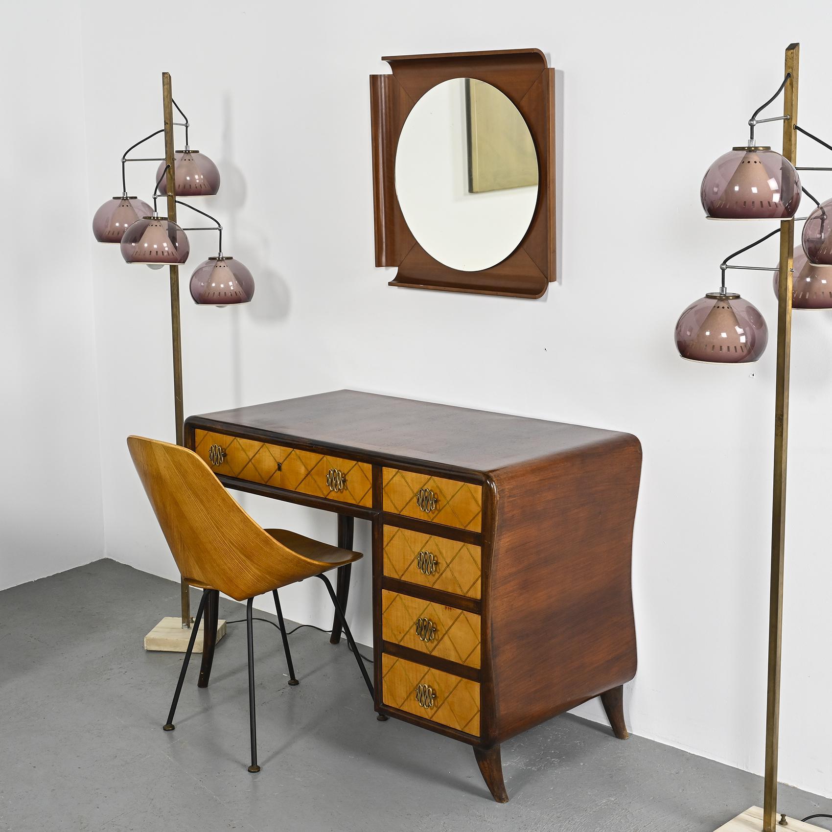 An Italian desk dating back to the 1940s and attributed to Osvaldo Borsani.

The entire structure, crafted from walnut-stained beech, elegantly rests on a curved base. It boasts five storage drawers with marquetry-adorned fronts. The captivating