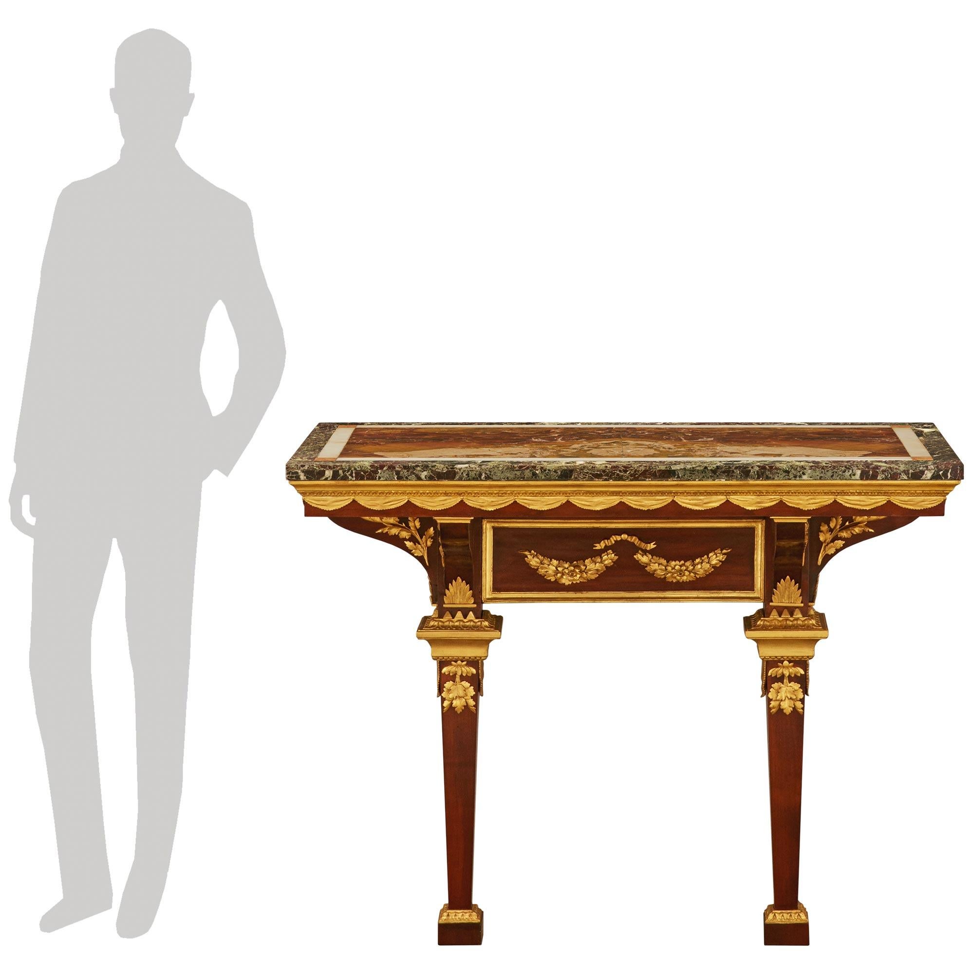 A stately and most decorative Northern Italian early 19th century Empire st. patinated Mahogany, Giltwood and veneered marble console. This stunning console is raised by square block feet with Giltwood sabots and capitals, as well as richly chased