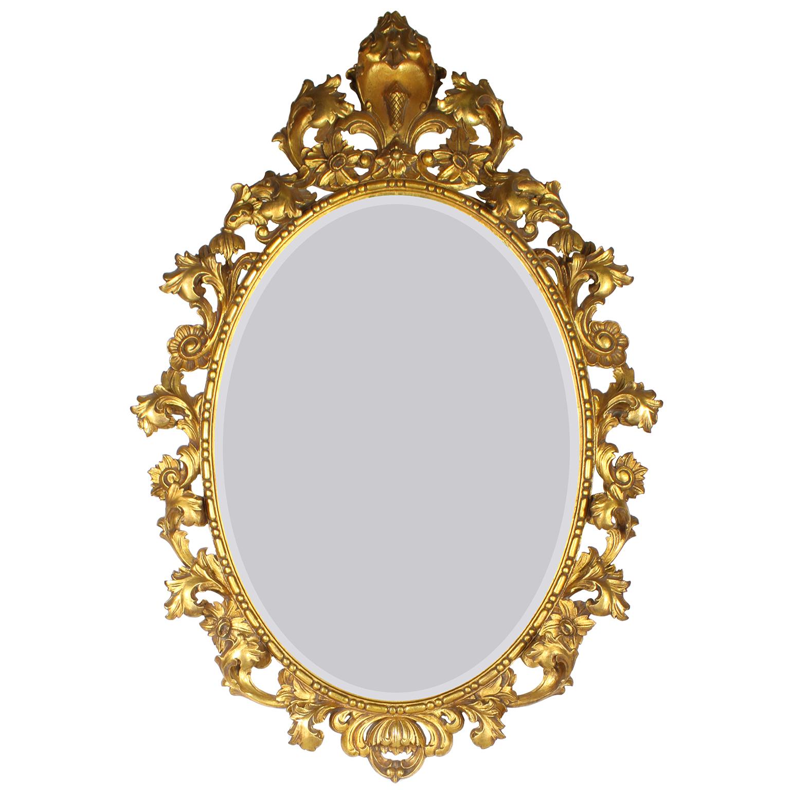 Eine italienische, vergoldete, holzgeschnitzte Spiegel- und Konsolengarnitur mit Marmorplatte. Der ovale Spiegelrahmen aus vergoldetem Holz ist mit einem floralen und verschnörkelten Akanthusmotiv verziert, mit einem Eichelschild gekrönt und mit