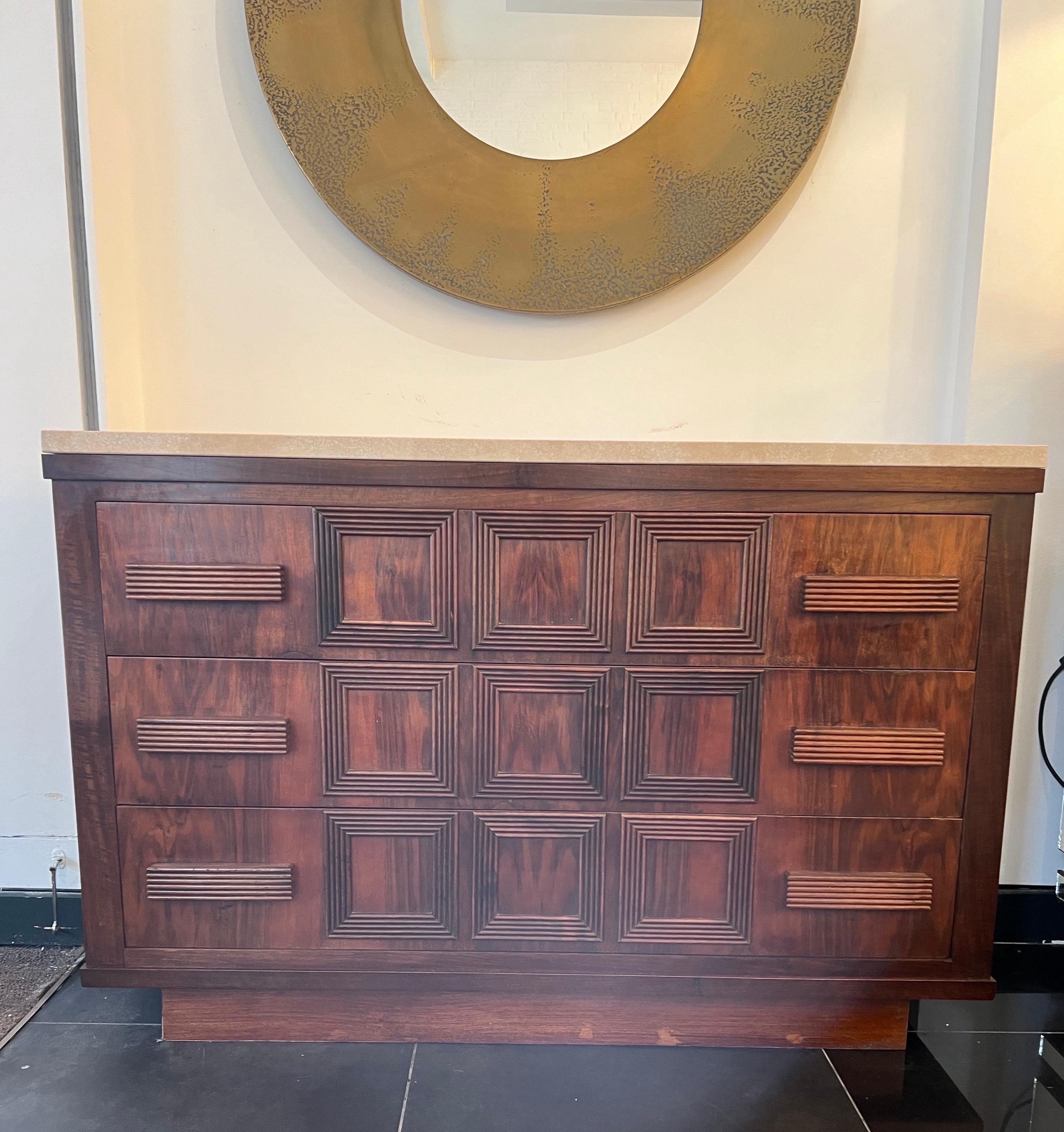 A fabulous geometric design three drawers commode made from dark chestnut wood with travertine top and reeded detailing to the front . This wonderful example of Italian craftsmanship was designed in the early 1950s . 
More photos available on