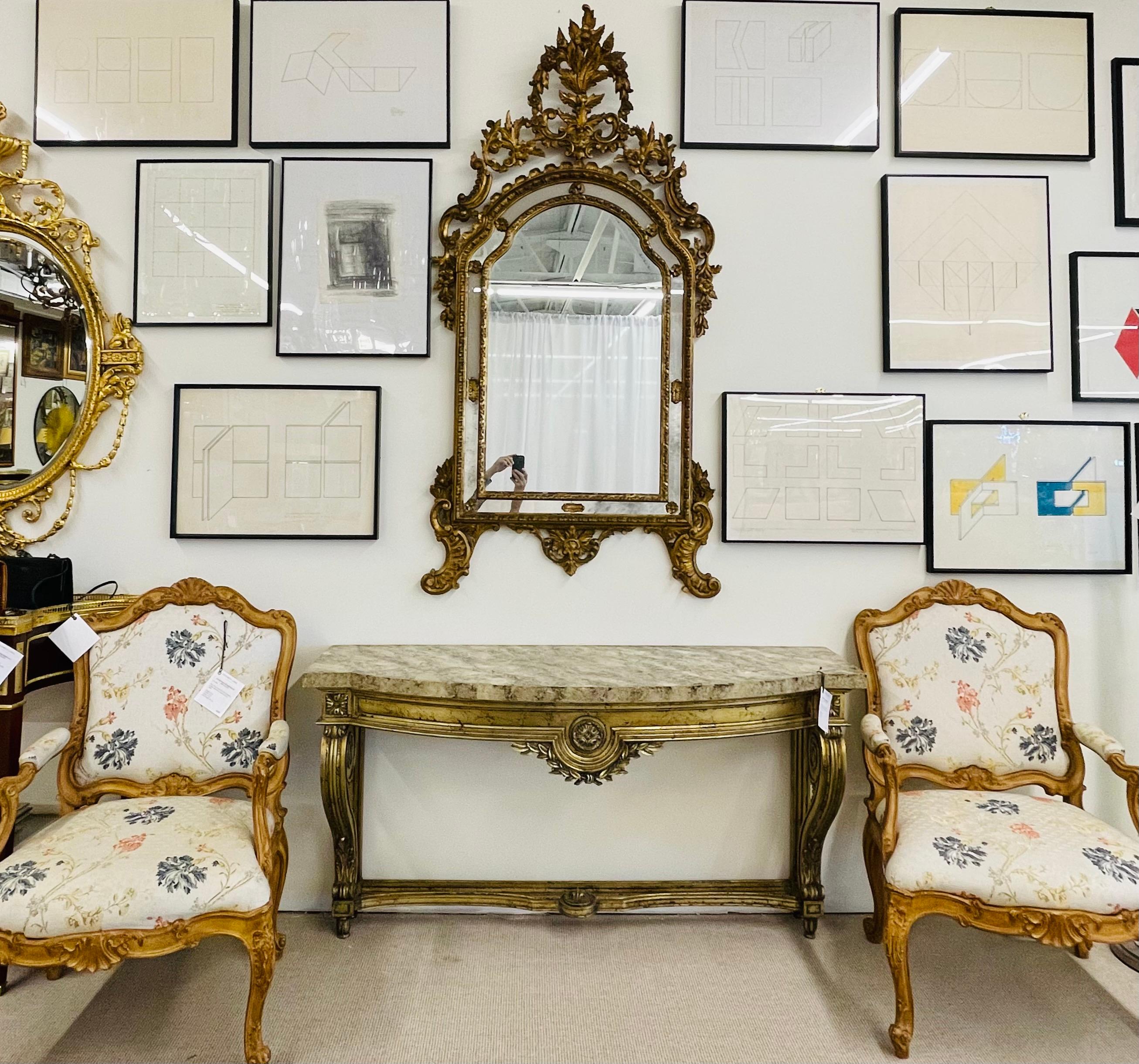 A large and impressive wall mirror having standing feet leading to a double framed center mirror with frosted and clear mirror sides flanked in gilt gesso design. The frame with leaves, floral and scroll design throughout.