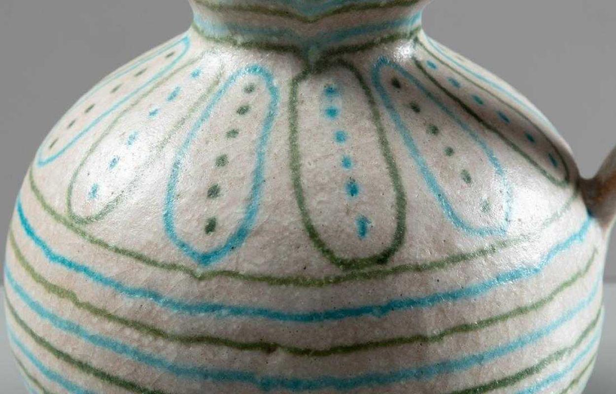 A stoneware pitcher by Guido Gambon, Italy, circa 1960s. Beautifully glazed in white a lava-like texture and decorated with blue and green lines, circles and dots. The geometrical pattern contrasts nicely with the Classic and organic shape of the