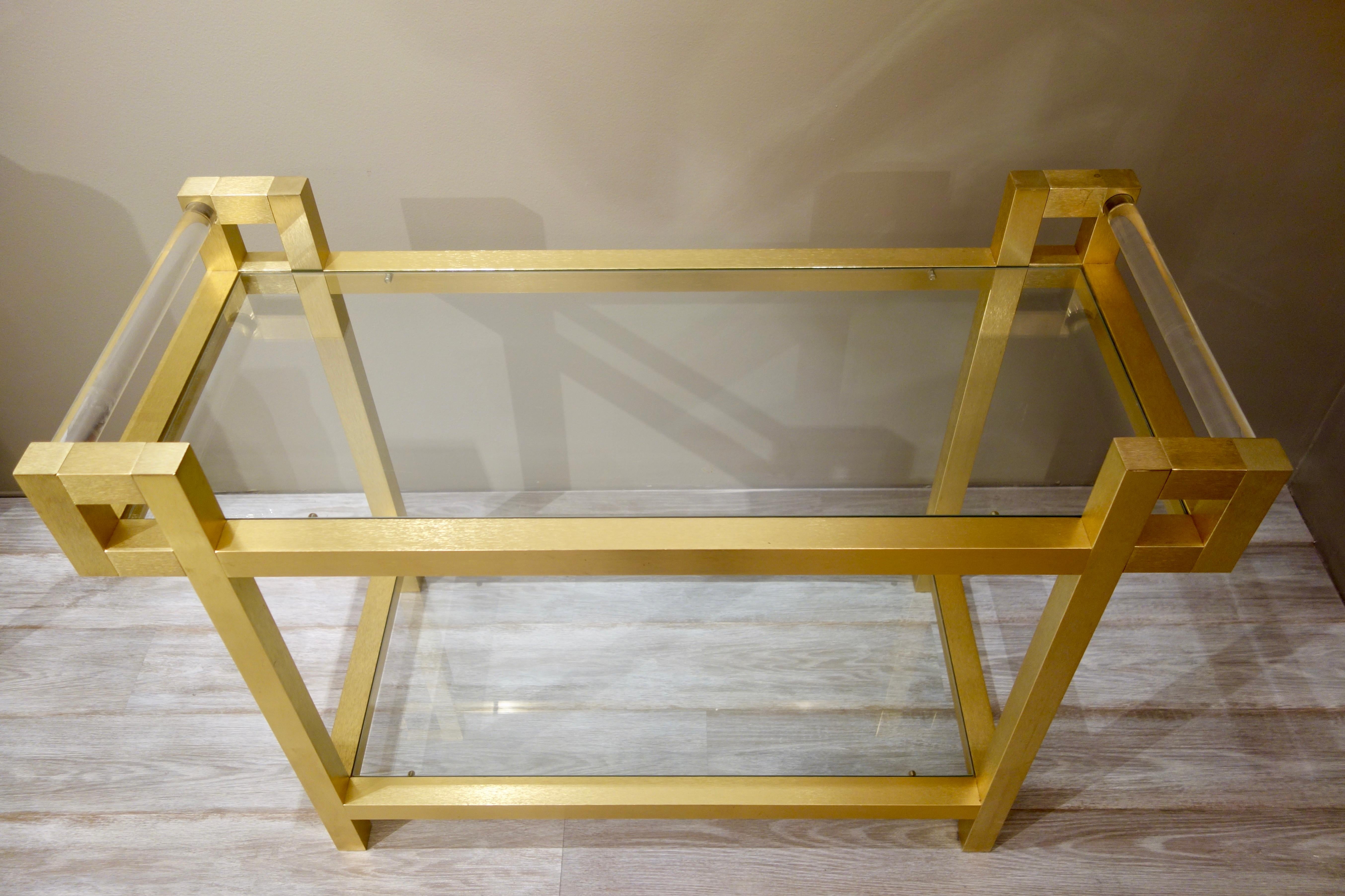 An Italian gold tone bar cart attributed to Romeo Rega, with two glass shelves and Lucite handles.