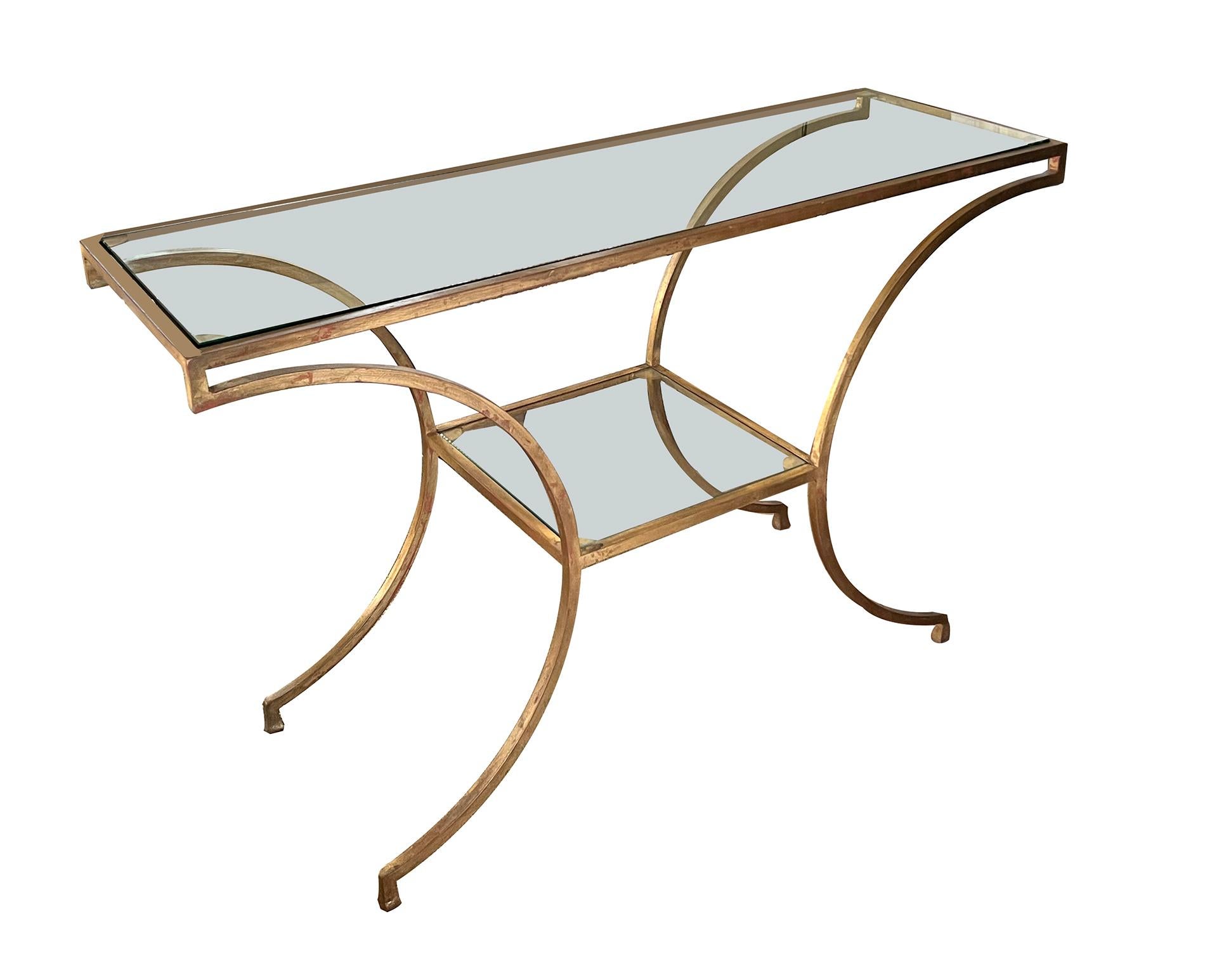 the inset rectangular glass top within a gilt-metal frame; raised on dramatically splayed supports ending in short graduated quadrangular feet all joined by a lower inset glass shelf