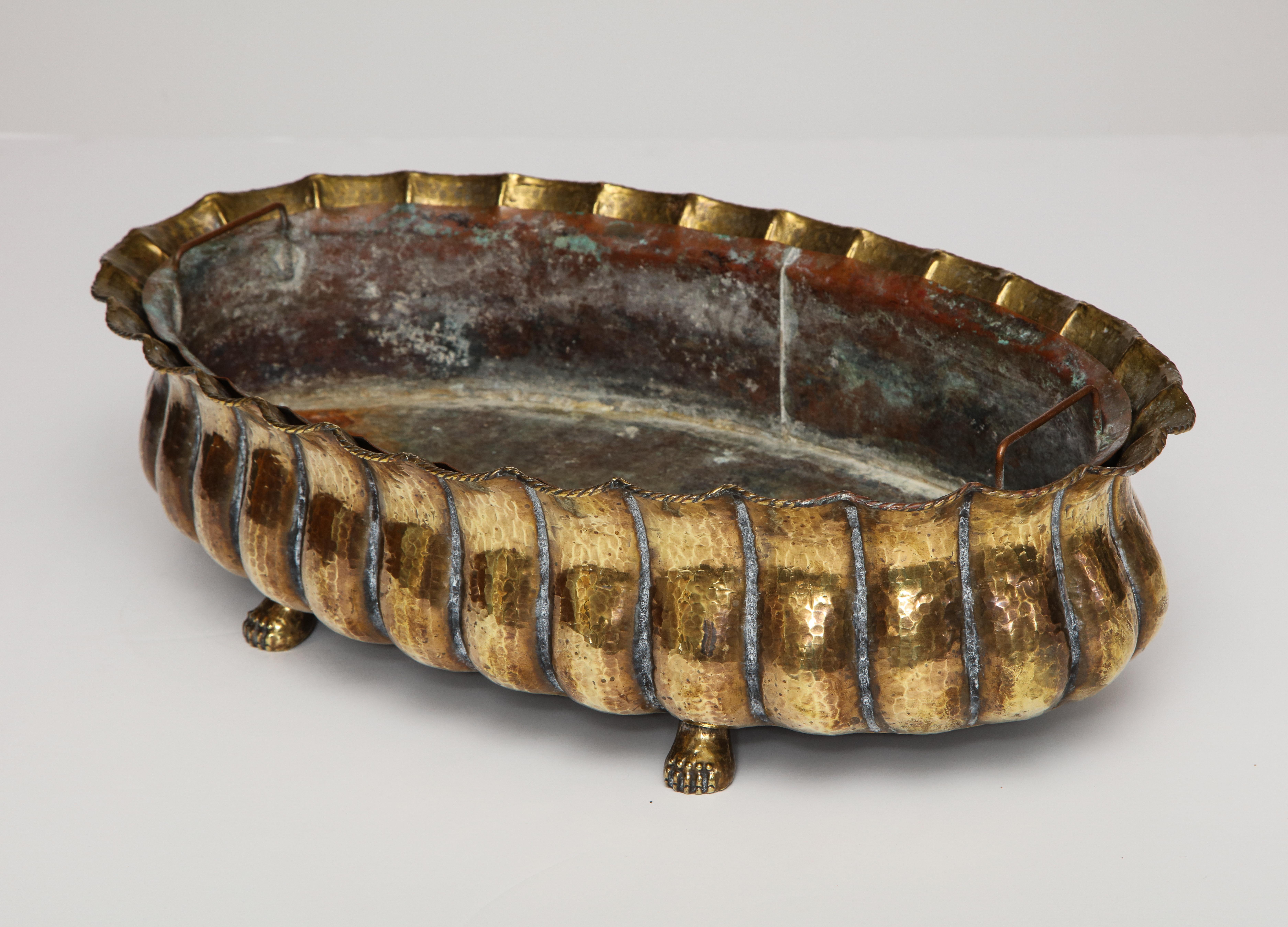 The brass oval ribbed jardinière with cast brass paw feet and original copper liner. Stamped on bottom 