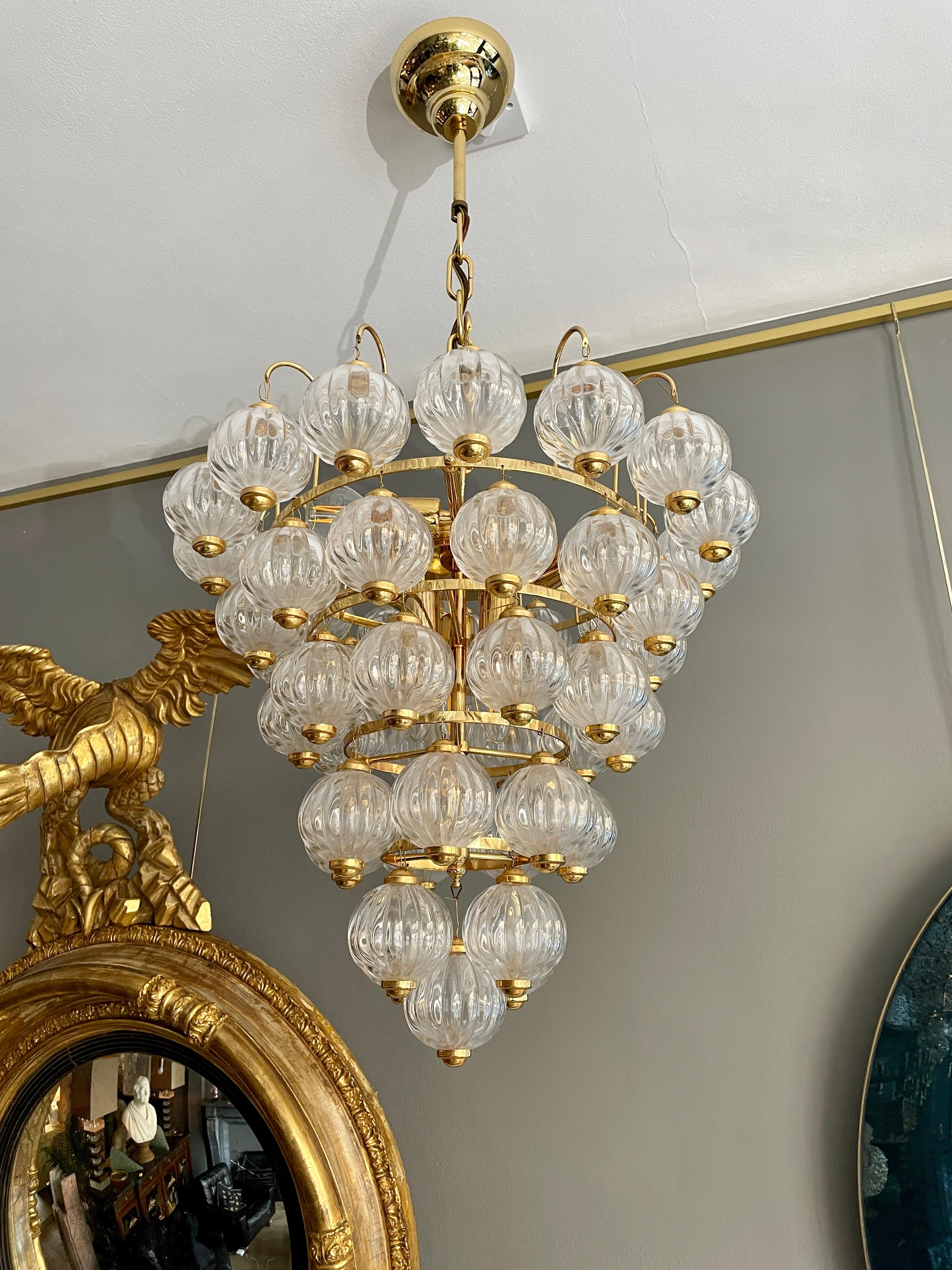 A six tier chandelier in brass with hand blown glass balls. Six light points within, probably by Pulegoso however very similar in style to Kalmar's Tulipan style chandelier. An unusual, warm and very pretty light. 

Continental circa 1970.