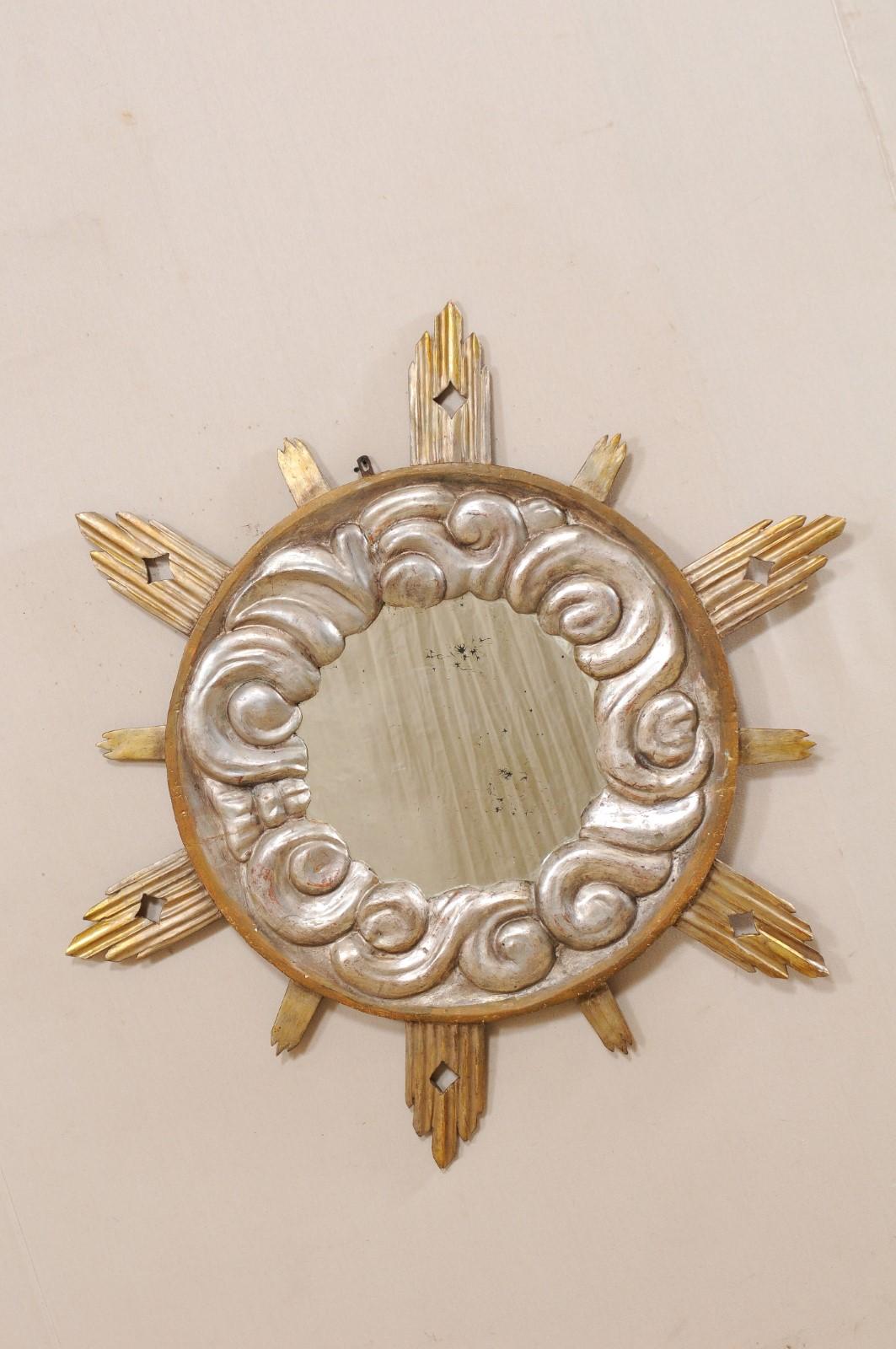 An exquisite larger size Italian cloudy sunburst mirror from the 19th century. This antique mirror from Italy features a circle-shaped frame with silver colored cloudy surround, with gilded sun-rays emerging outward in varying lengths, with the